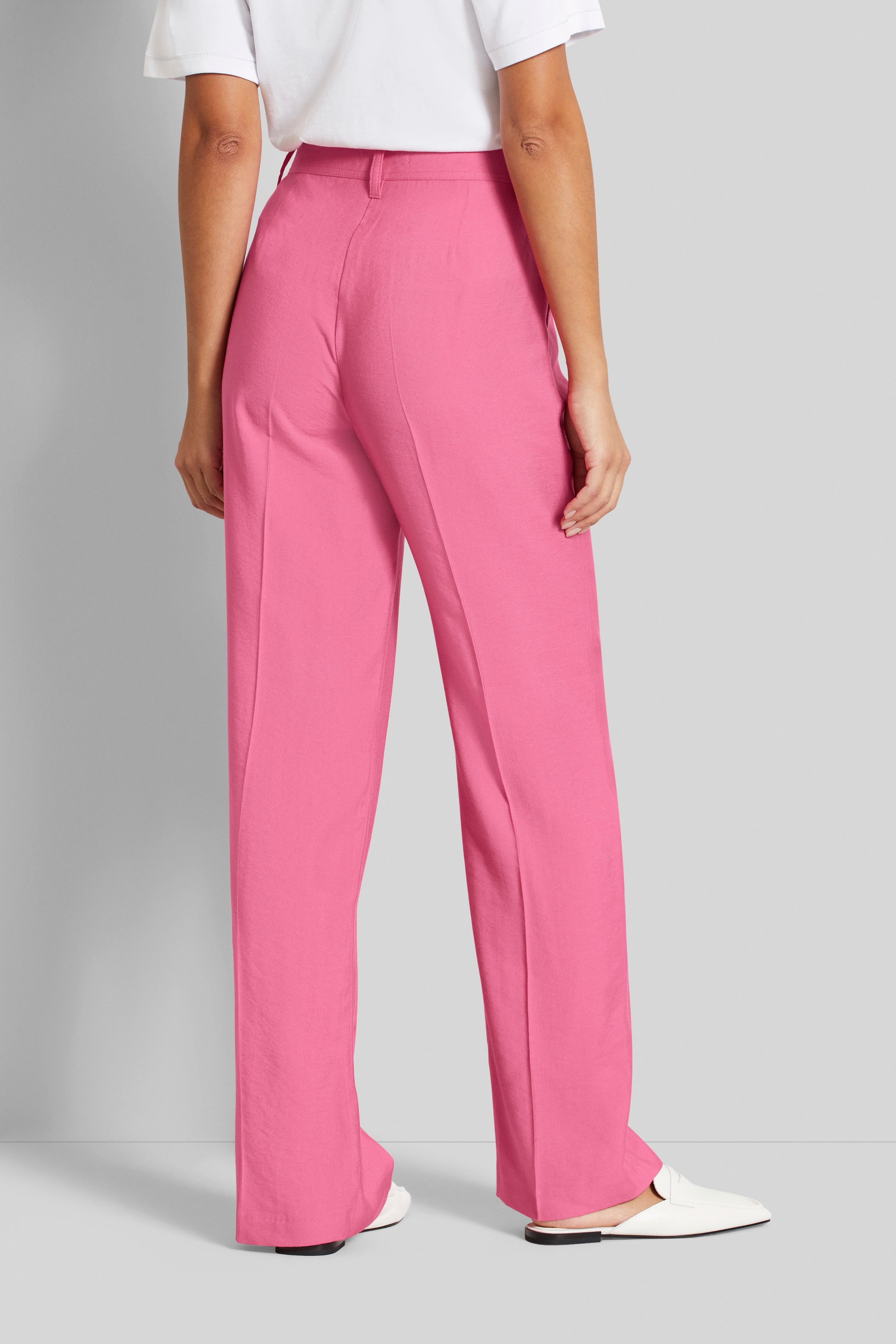 Brede modelopname met roze broek en wit T-shirt van bugatti, ontspannen houding.