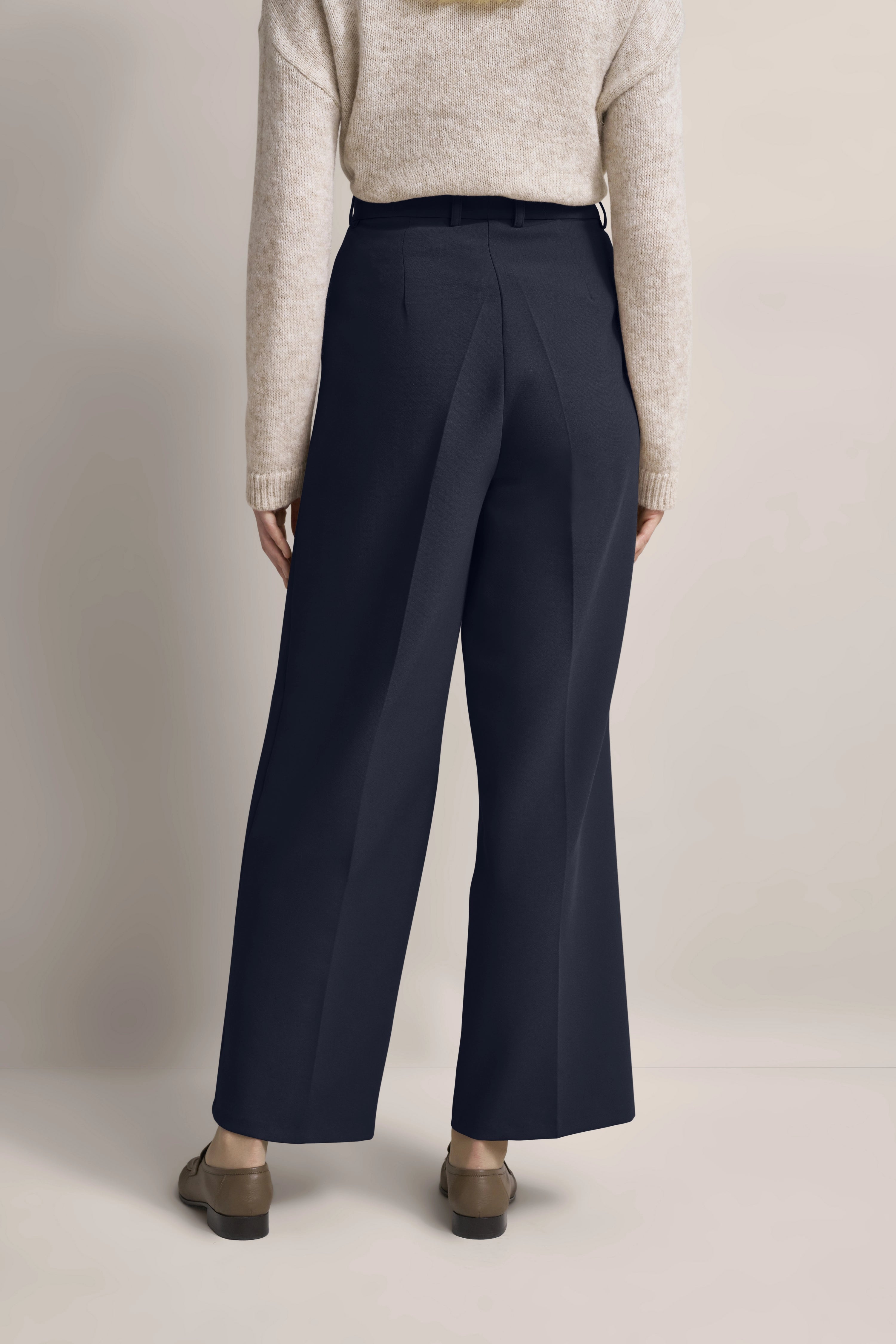 Beige Pullover und dunkelblaue Hose, Modelbild von hinten, lässige Pose.