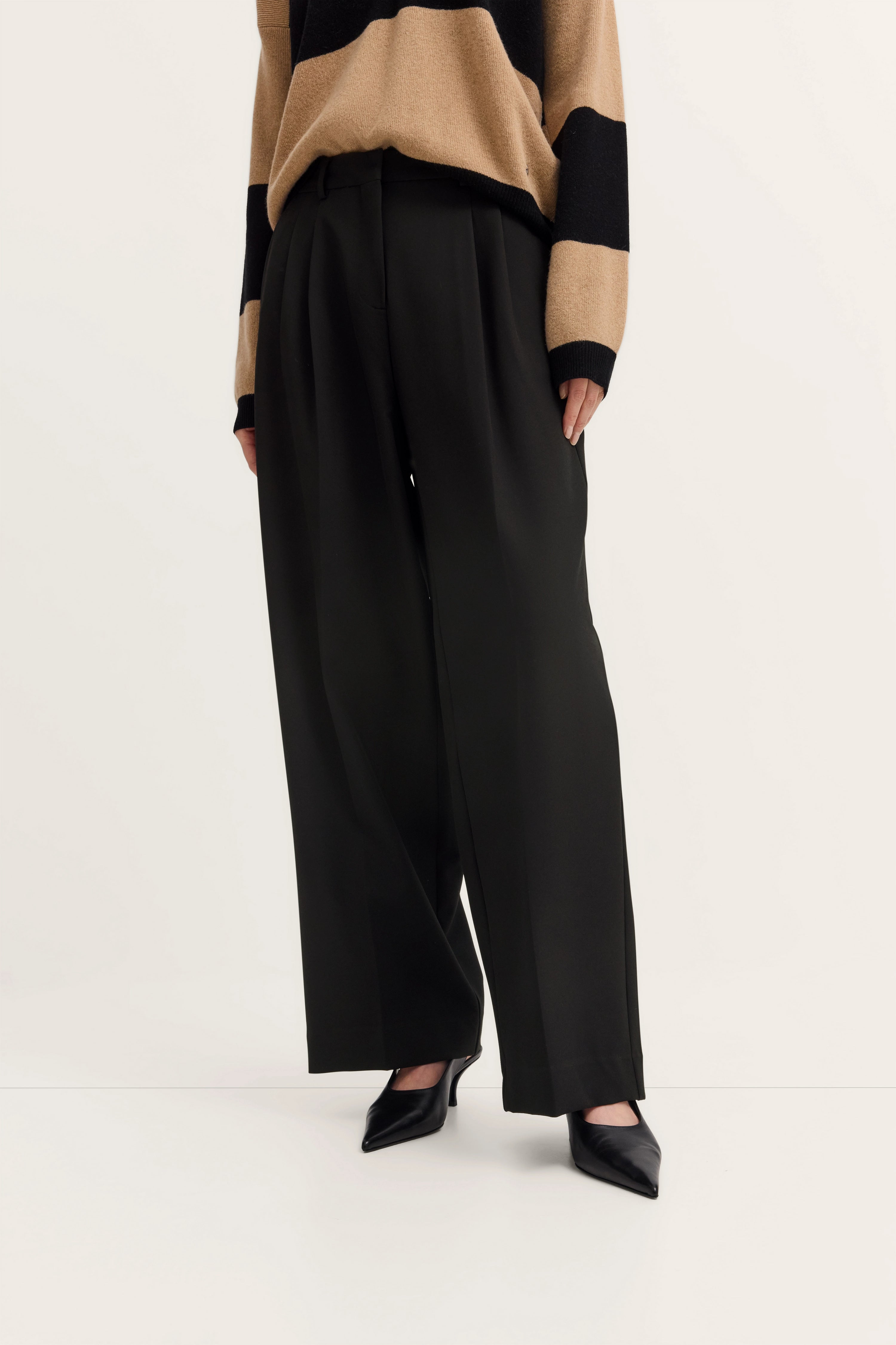 Beiger Streifenpullover und schwarze weite Hose, legeres Modelbild, bugatti Stil.
