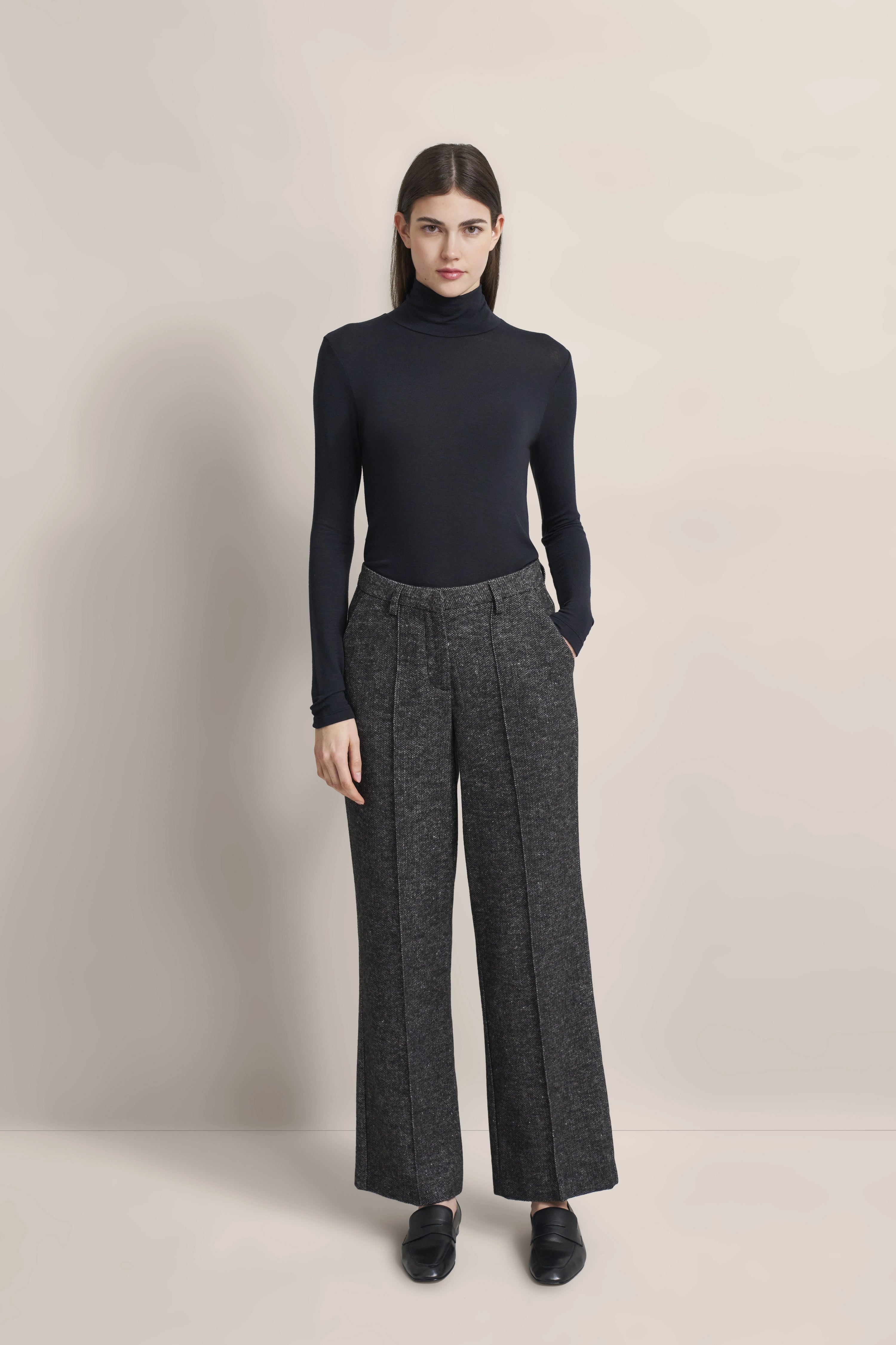 Model trägt schwarzen Rollkragenpullover, graue Hose