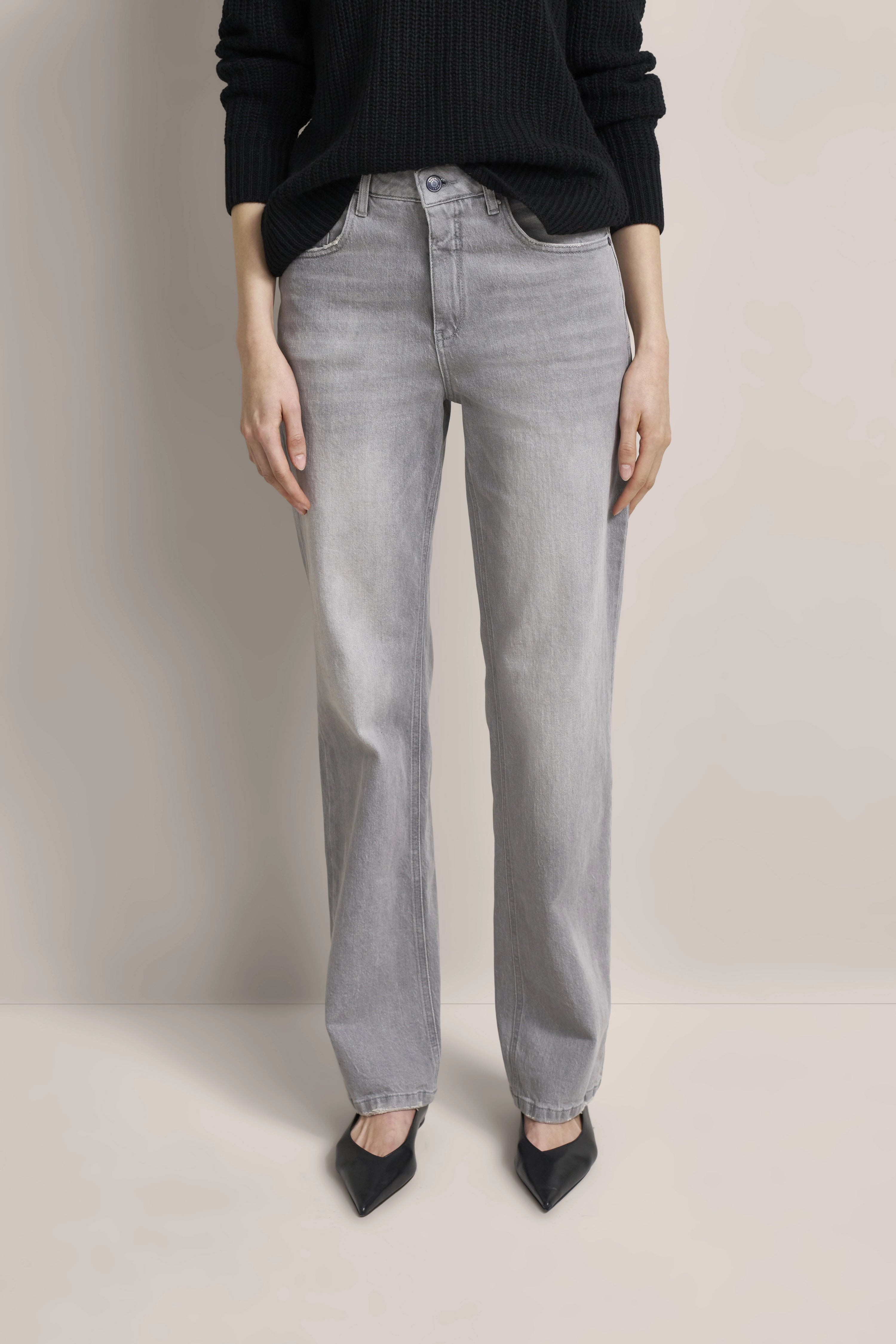 Graue Jeans mit schwarzem Strickpullover, legeres Modelbild.