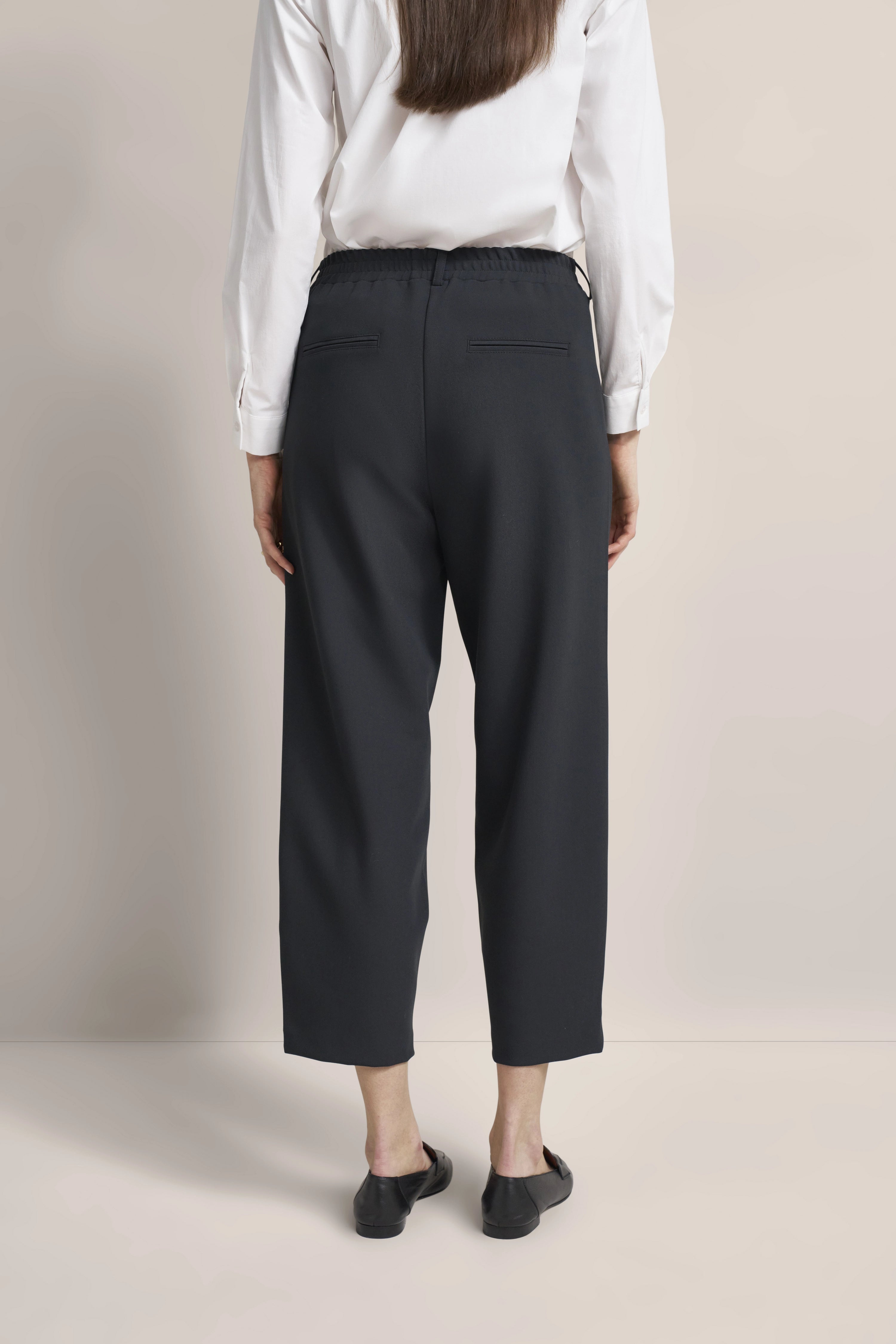 Weißes Hemd und schwarze Hose, Model von hinten, lässige Pose, bugatti Stil.