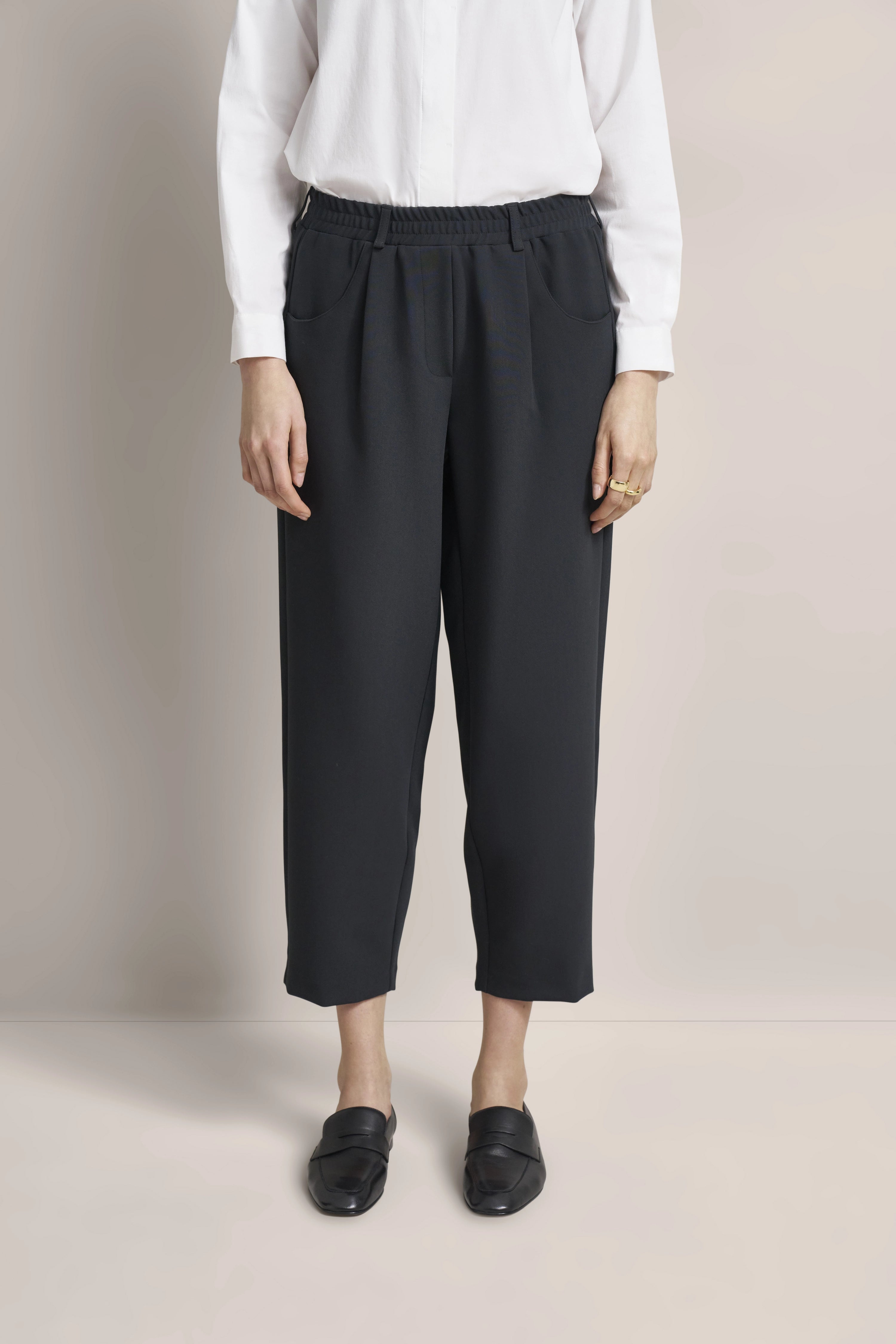 Weißes Hemd, schwarze Hose, schwarze Loafer, Modelbild, entspanntes Posing.