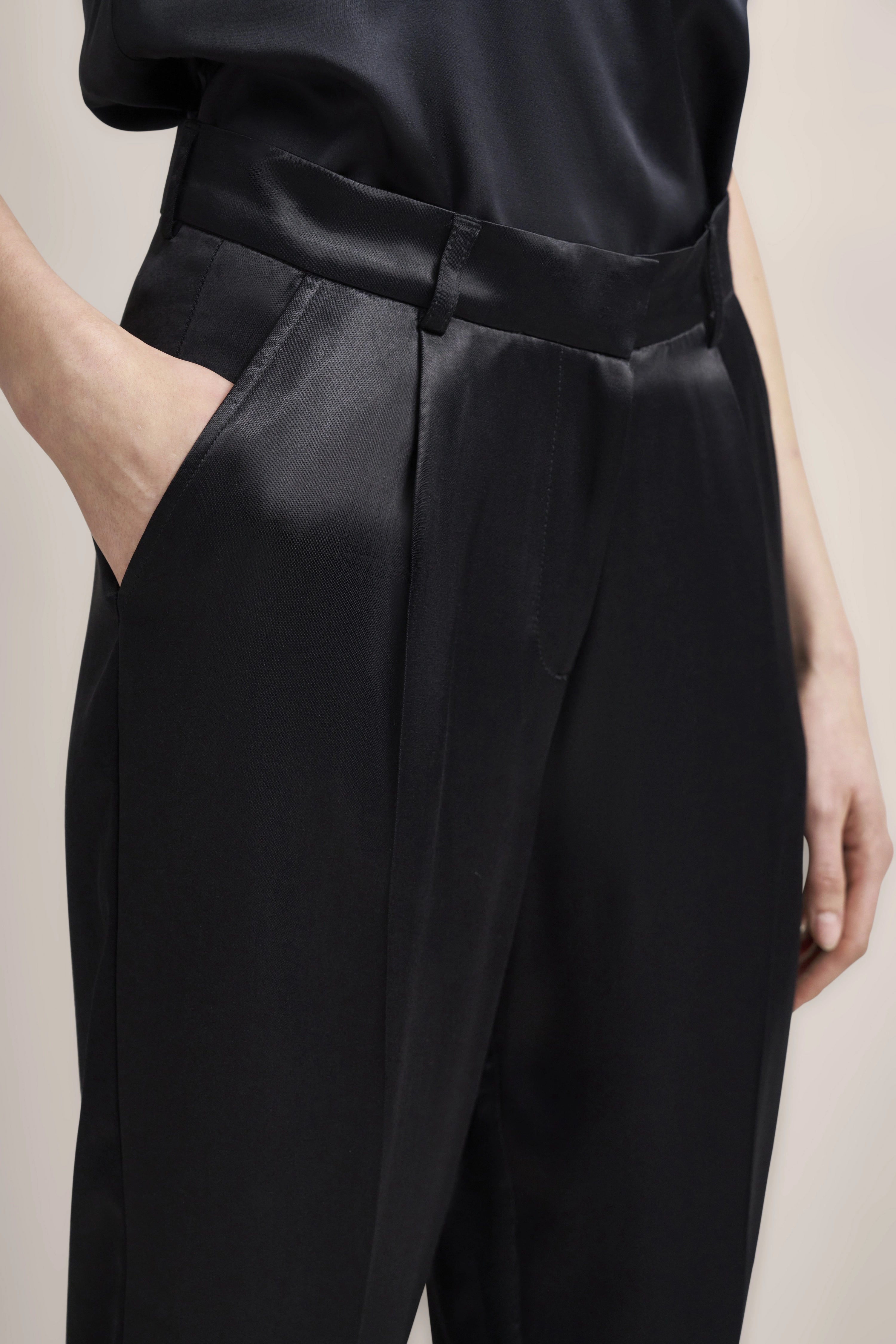 Schwarze Satin-Hose von bugatti, leger mit Hand in der Tasche, zeitlos elegant.