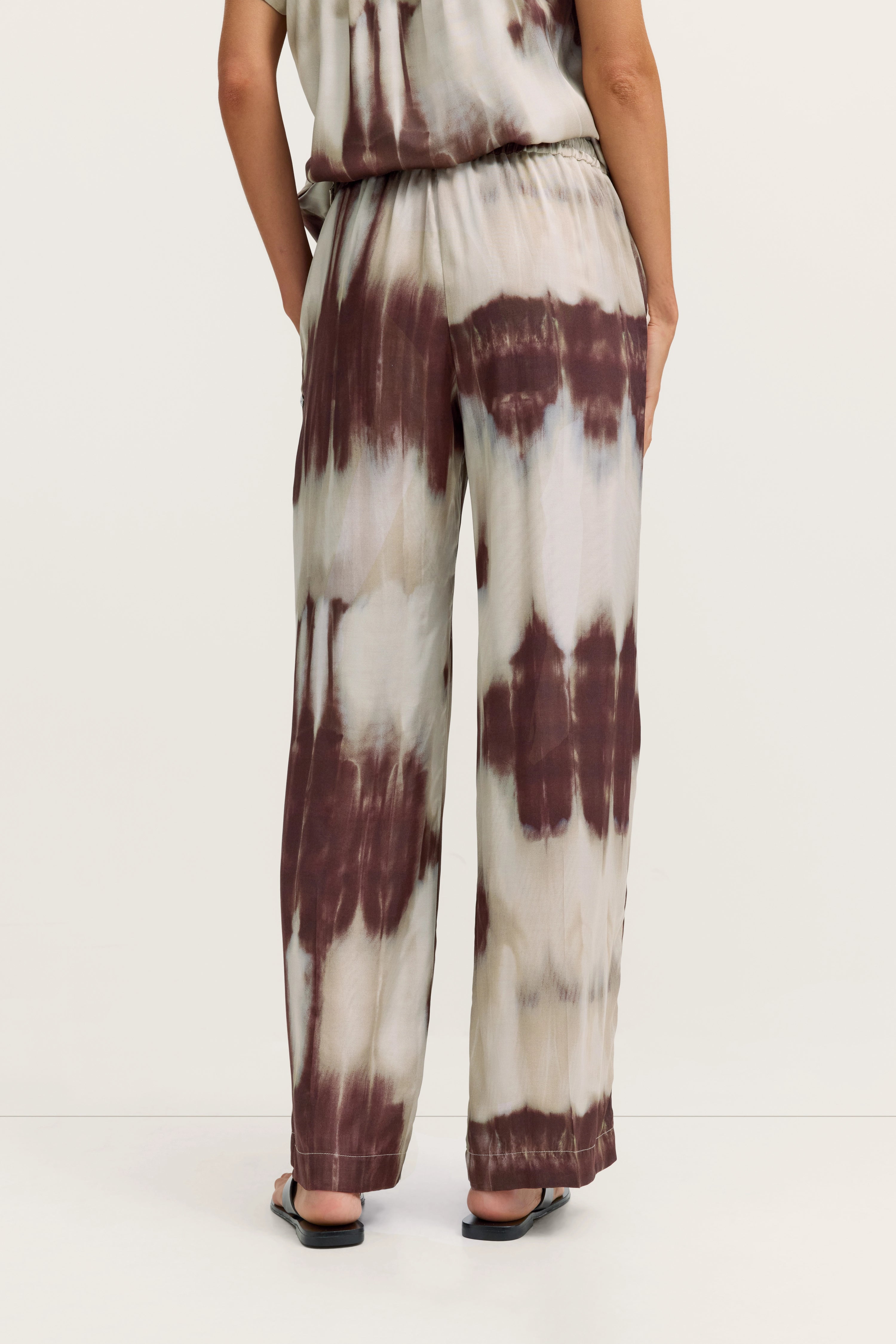 Legeres Modelbild, braun-weißes Batik-Outfit von bugatti, entspannte Rückenansicht, fließender Stoff.
