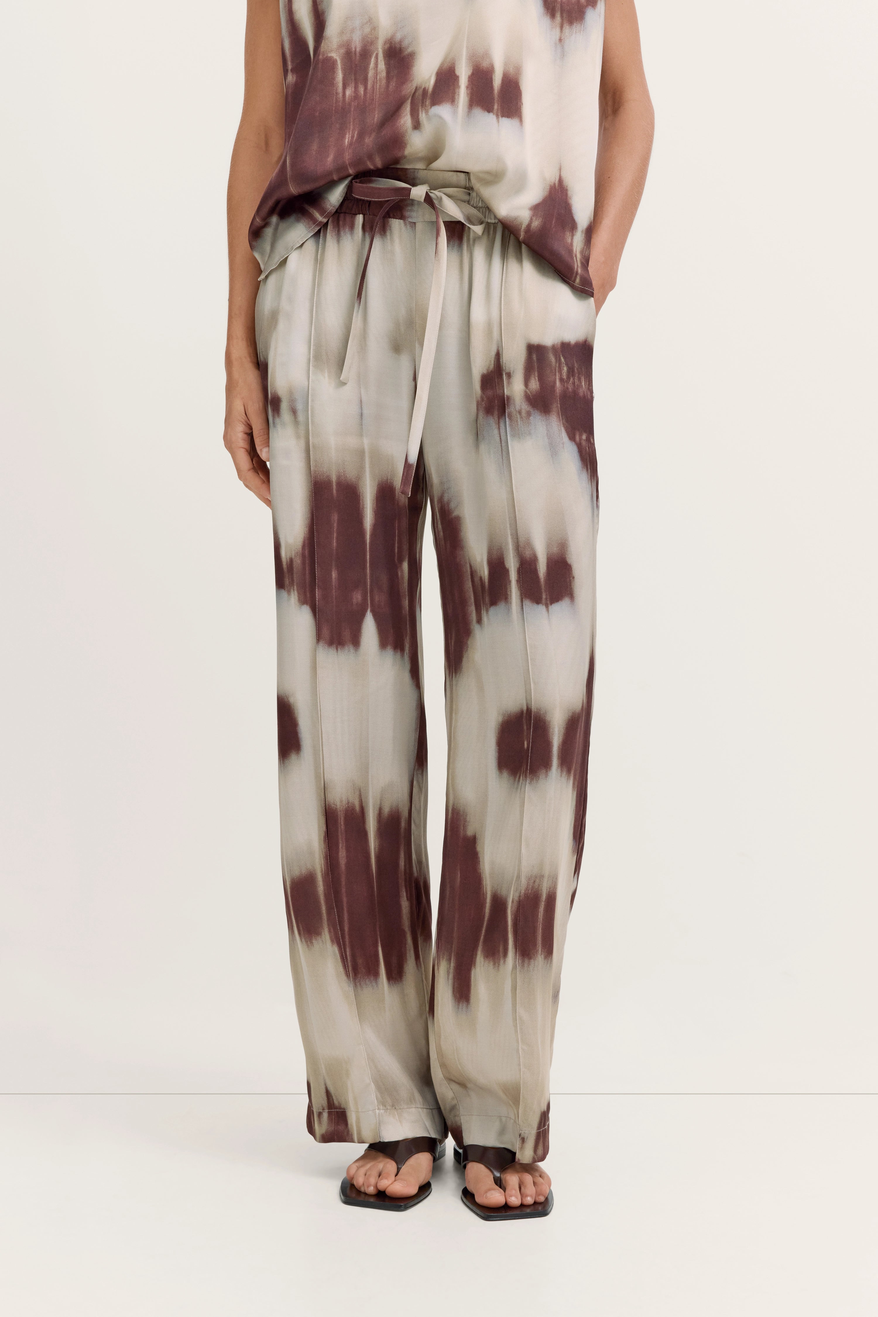 Legerbild: Weite Hose und Top in beige-braunem Batikmuster, lässig mit Bindegürtel.