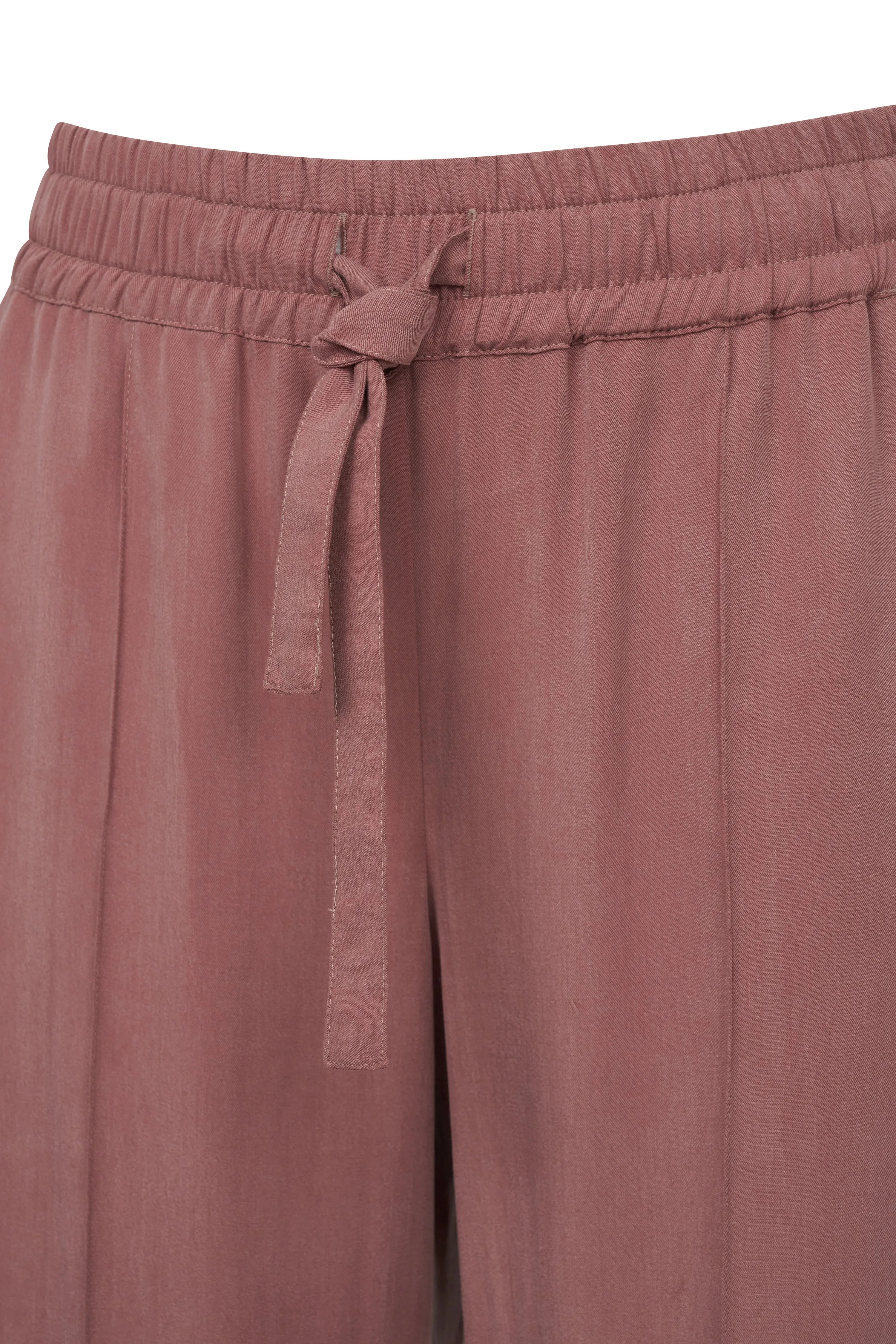 Roze bugatti-broek met elastische tailleband en strik, detailopname.