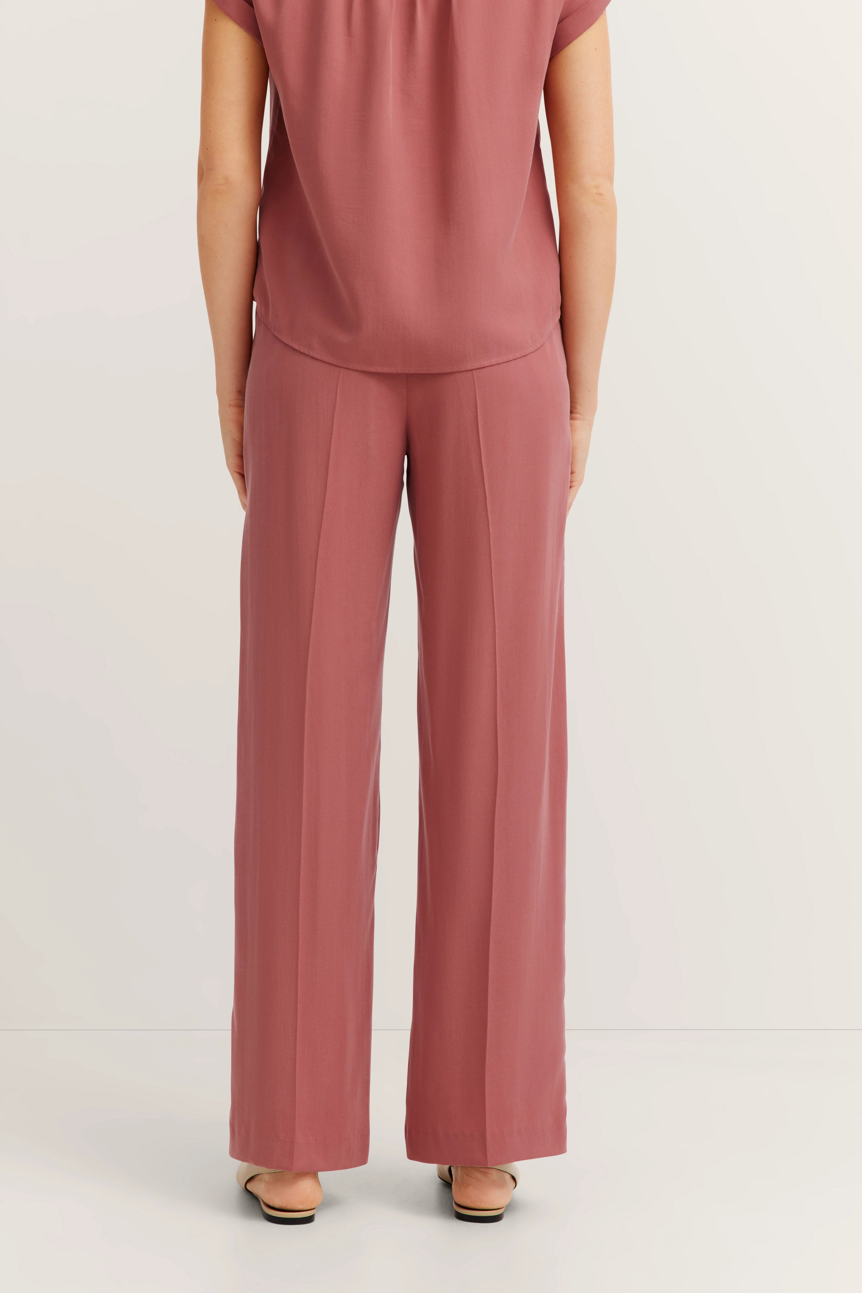 Achteraanzicht van een casual outfit met roze top en broek van bugatti.