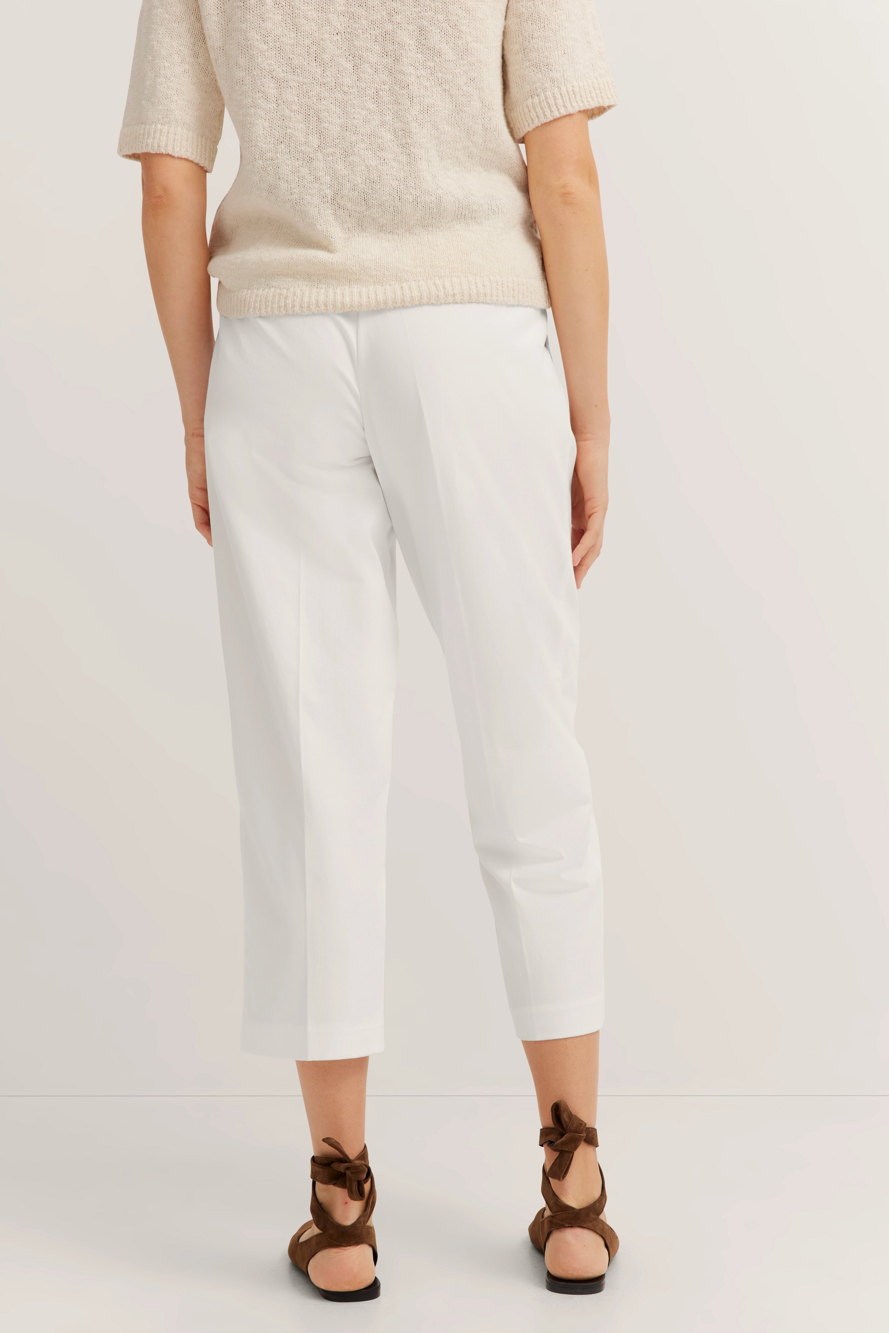 Beige trui en witte broek, casual modelbeeld, achteraanzicht, bruine sandalen.