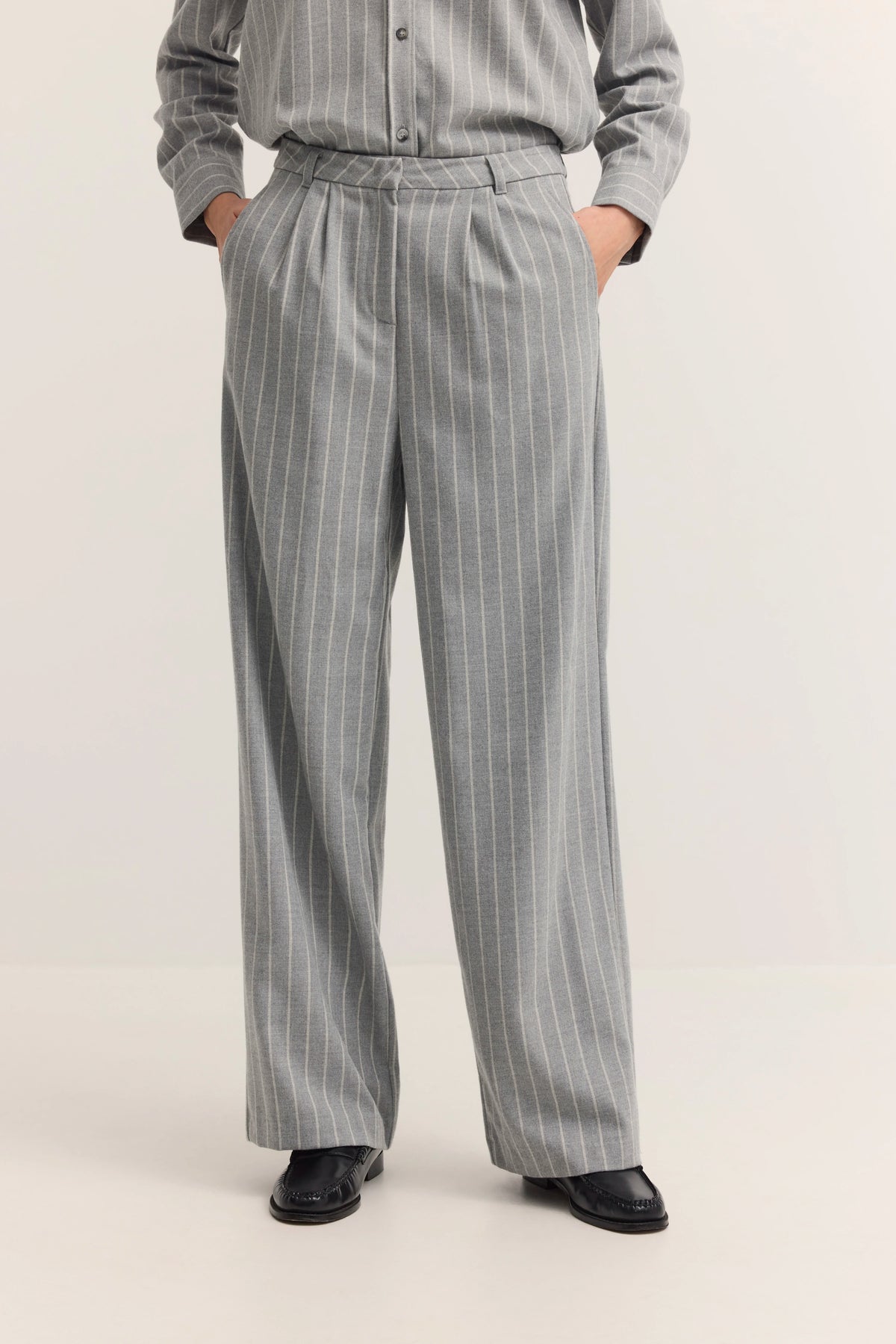 Graue Nadelstreifen-Hose, legeres Modelbild, Hände in Taschen, bugatti Stil und Eleganz.