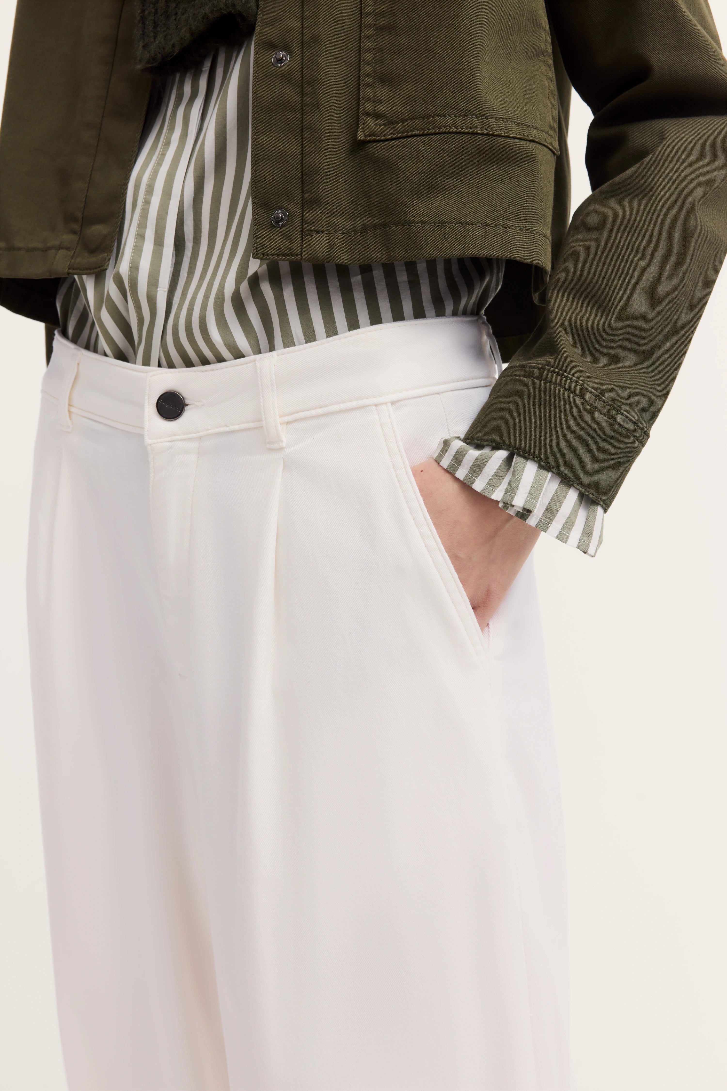 Grünes Streifenhemd mit olivgrüner Jacke und weißen Hosen, legeres Büstenbild.