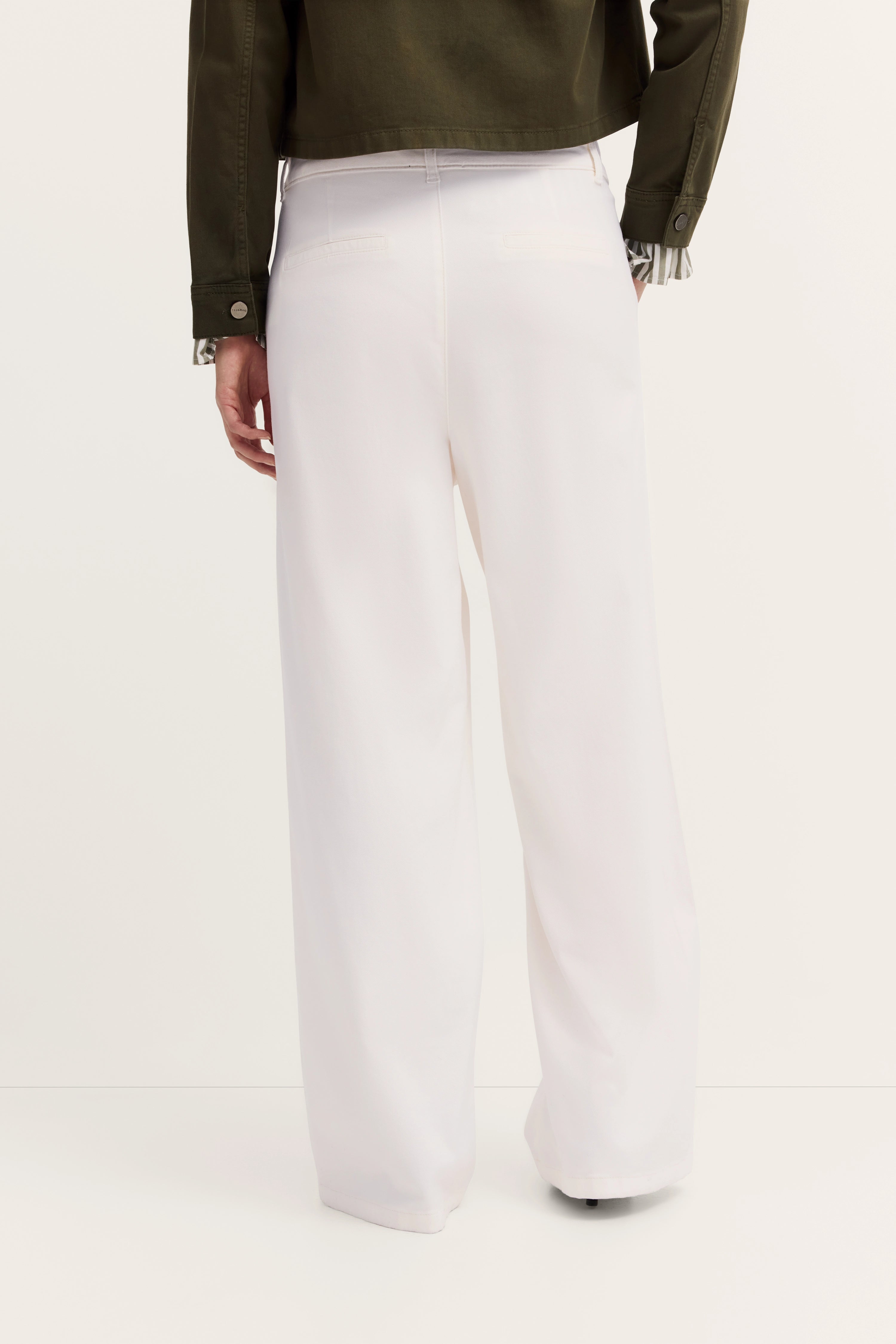 Weißer Hosenanzug mit olivgrüner Jacke, legeres Modelbild, Rückansicht.