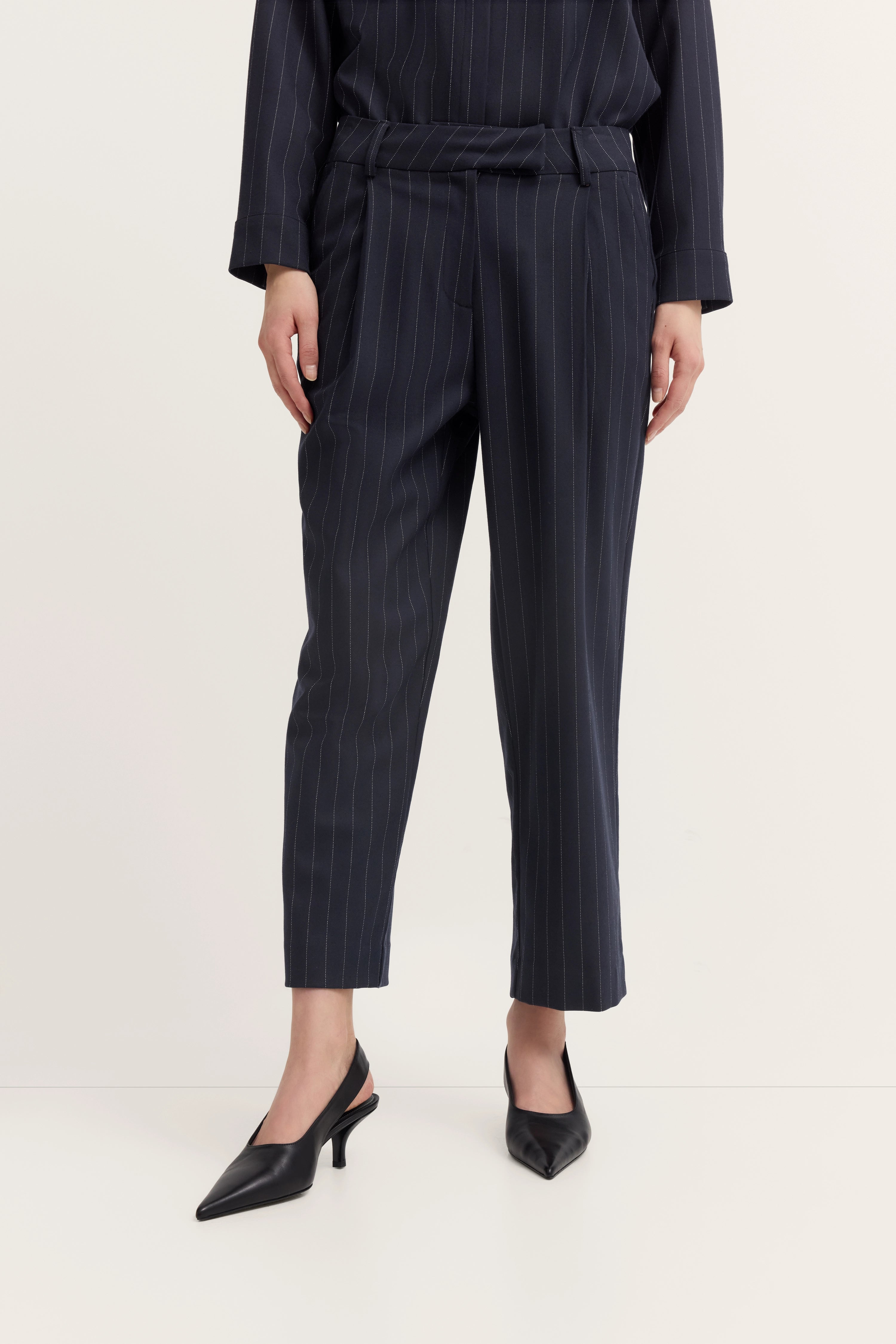 Dunkelblauer Nadelstreifenanzug mit Hose und Jacke, Büstenbild, elegante schwarze Pumps.