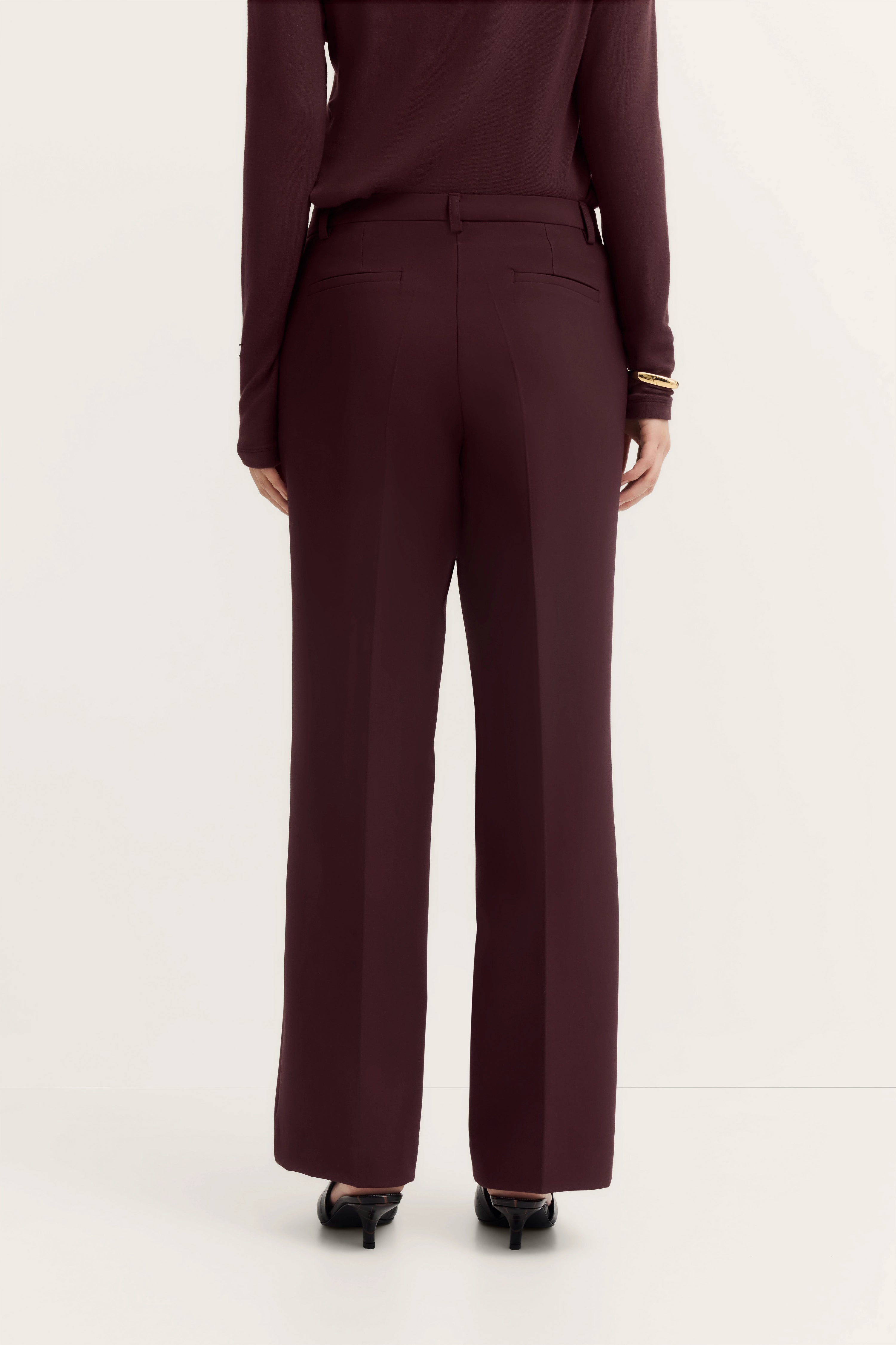 Bugatti Outfit in Bordeaux, bestehend aus eleganter Hose und Oberteil, Model von hinten.