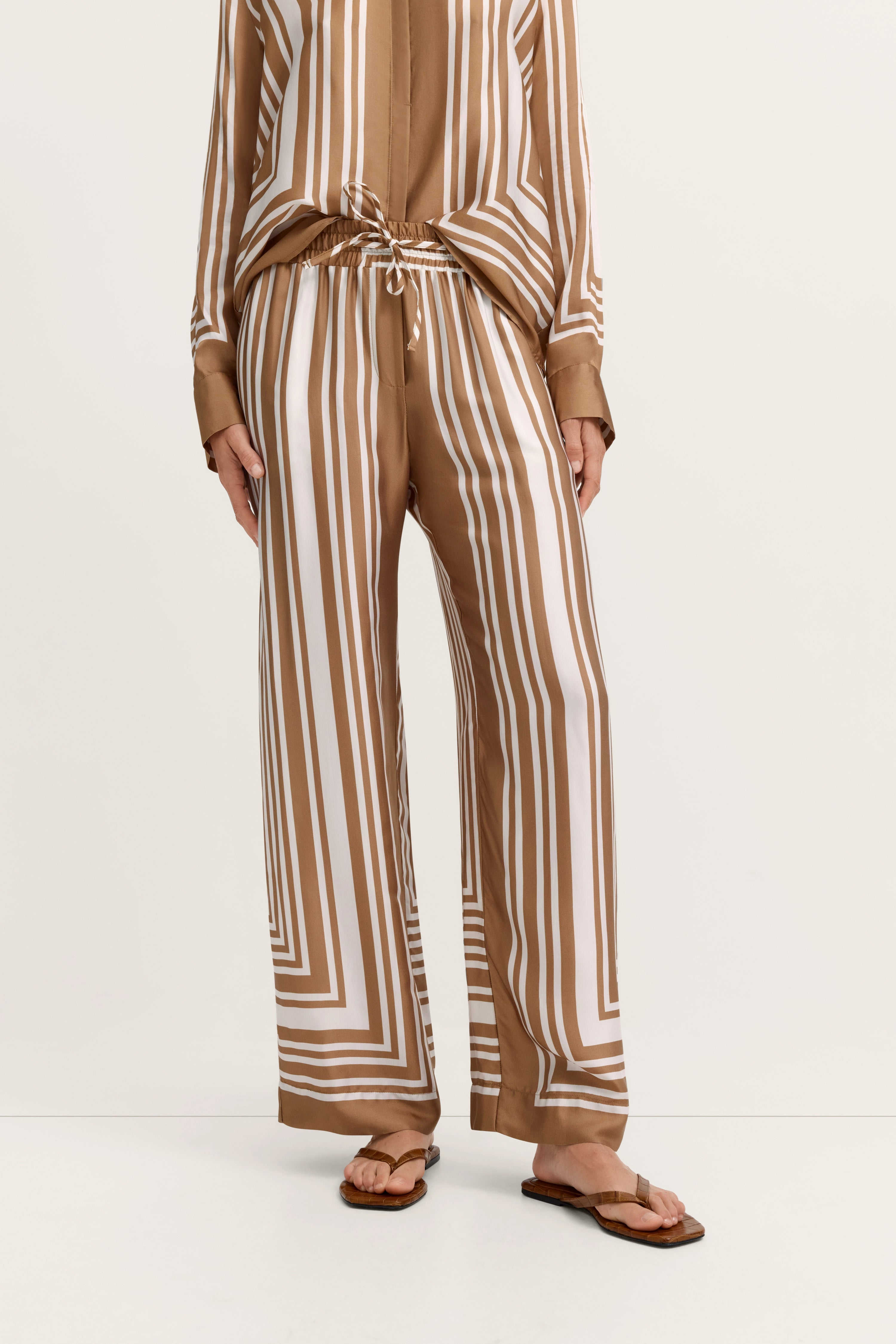 Braun-weiß gestreiftes bugatti Outfit, legeres Modelbild, entspanntes Stehen.