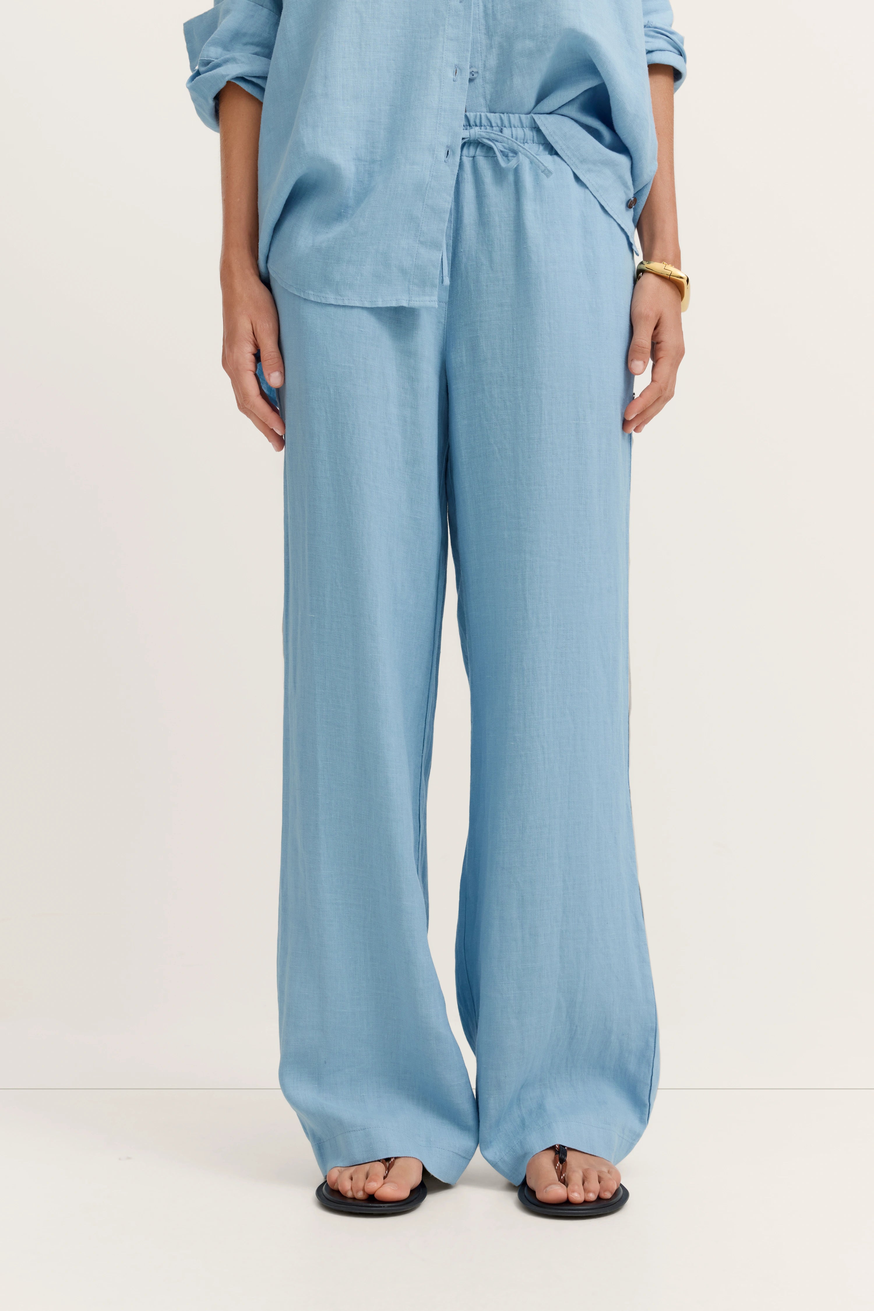 Blaues bugatti Outfit mit lockerer Bluse und weiter Hose, legeres Modelbild, entspannter Stand.