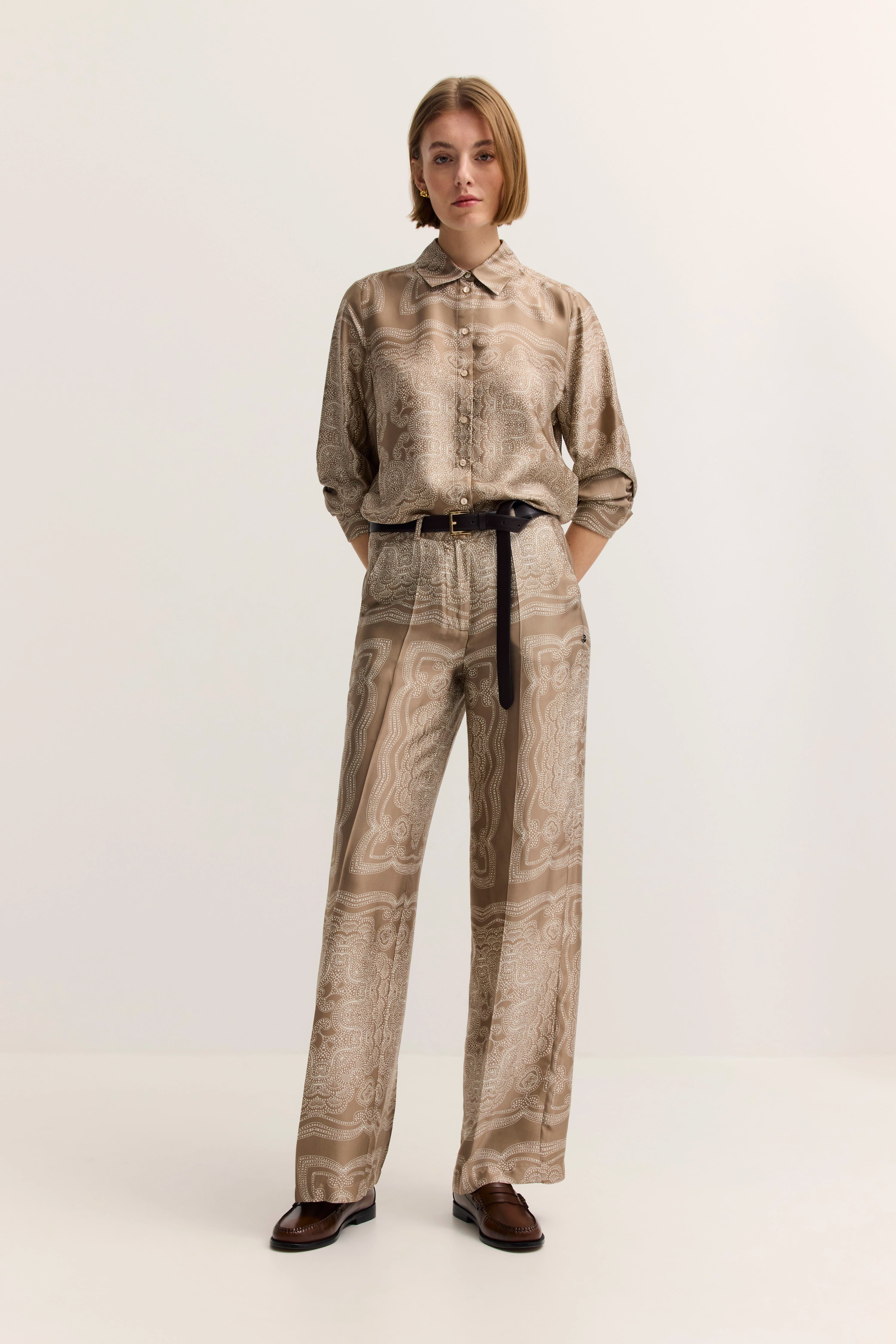 Beige gemustertes Seidenhemd und Hose Outfit, locker posierend, Modellbild.