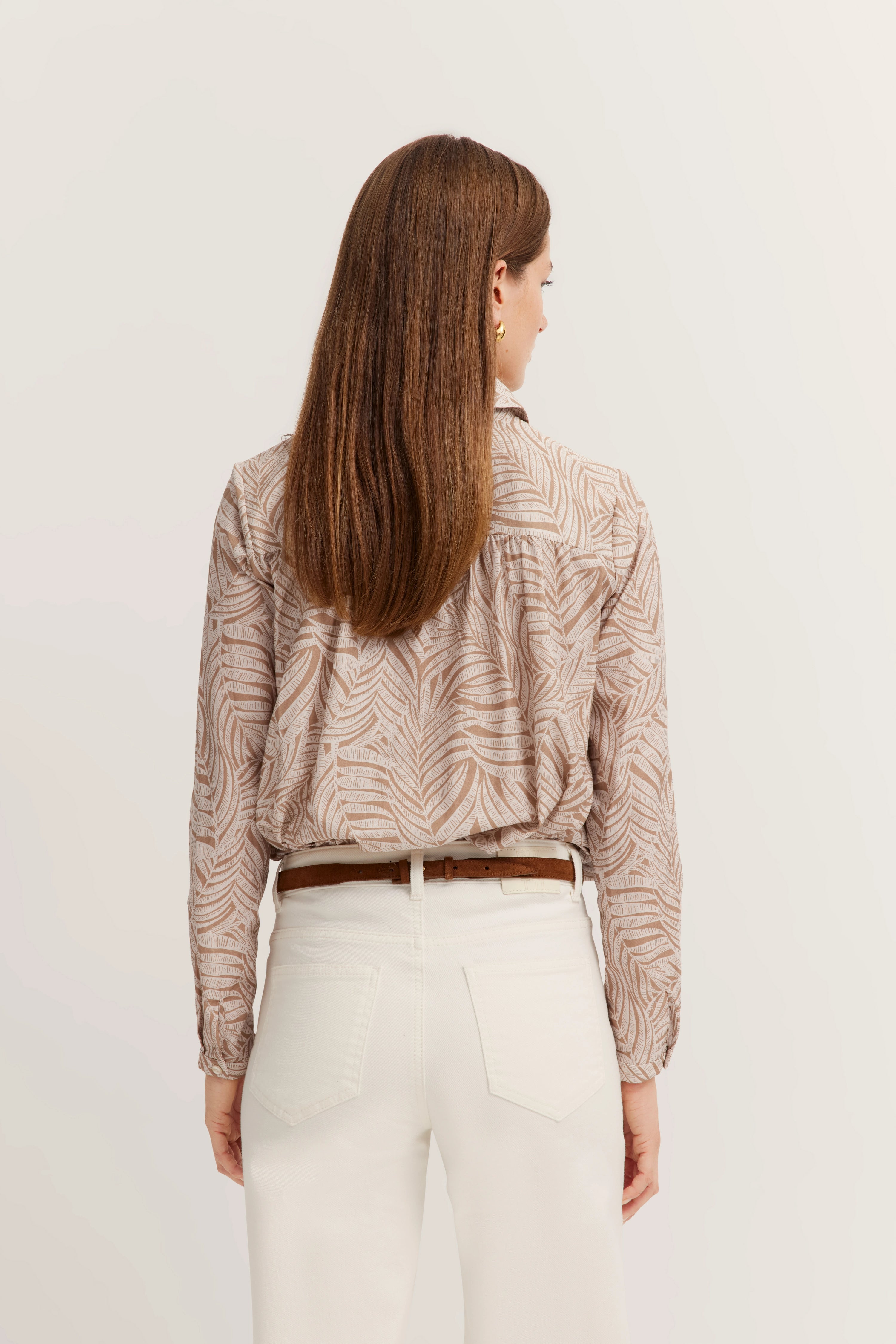 Bluse mit Blättermuster und weißer Hose, Model von hinten, lässige Bugatti Eleganz.