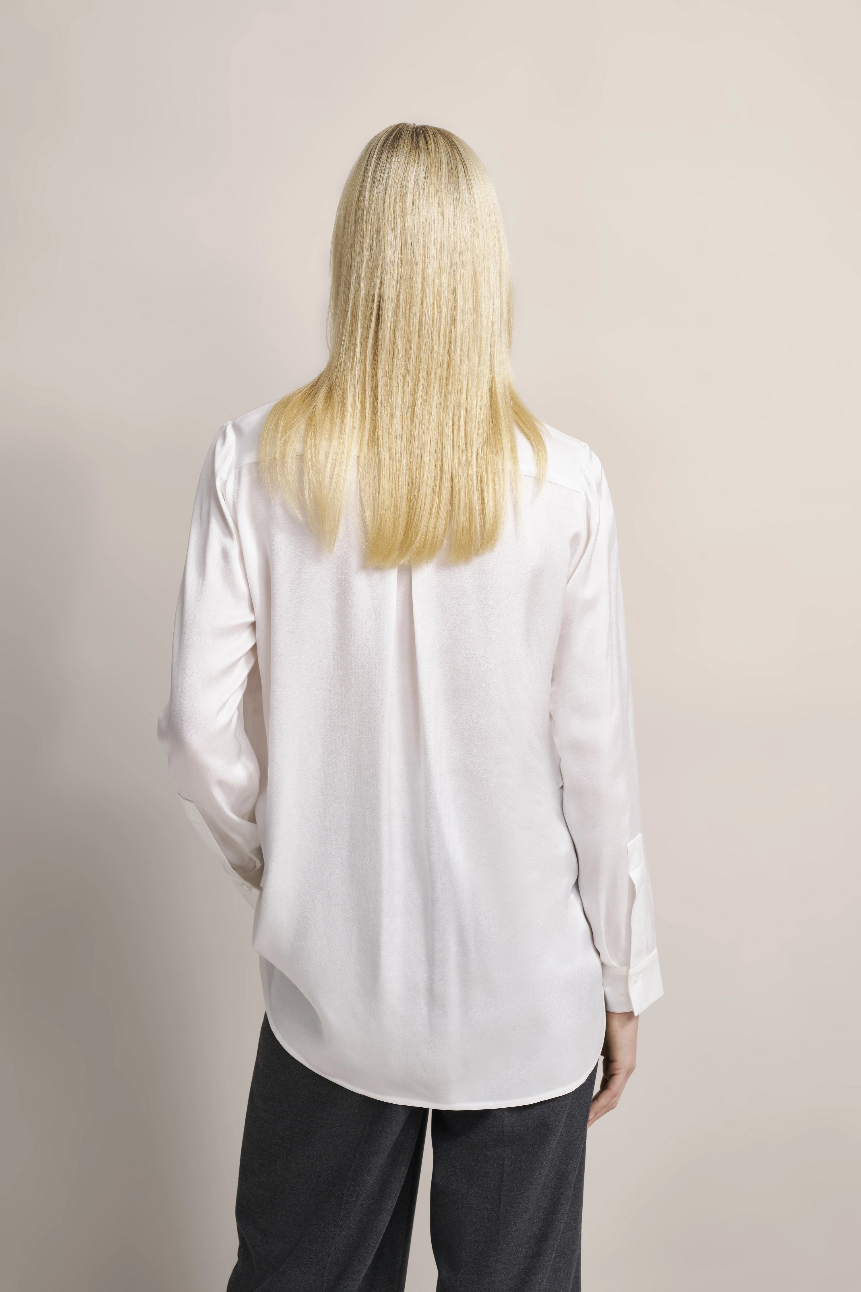 Weiße Bluse und graue Hose, Rückansicht, legeres Modelbild.
