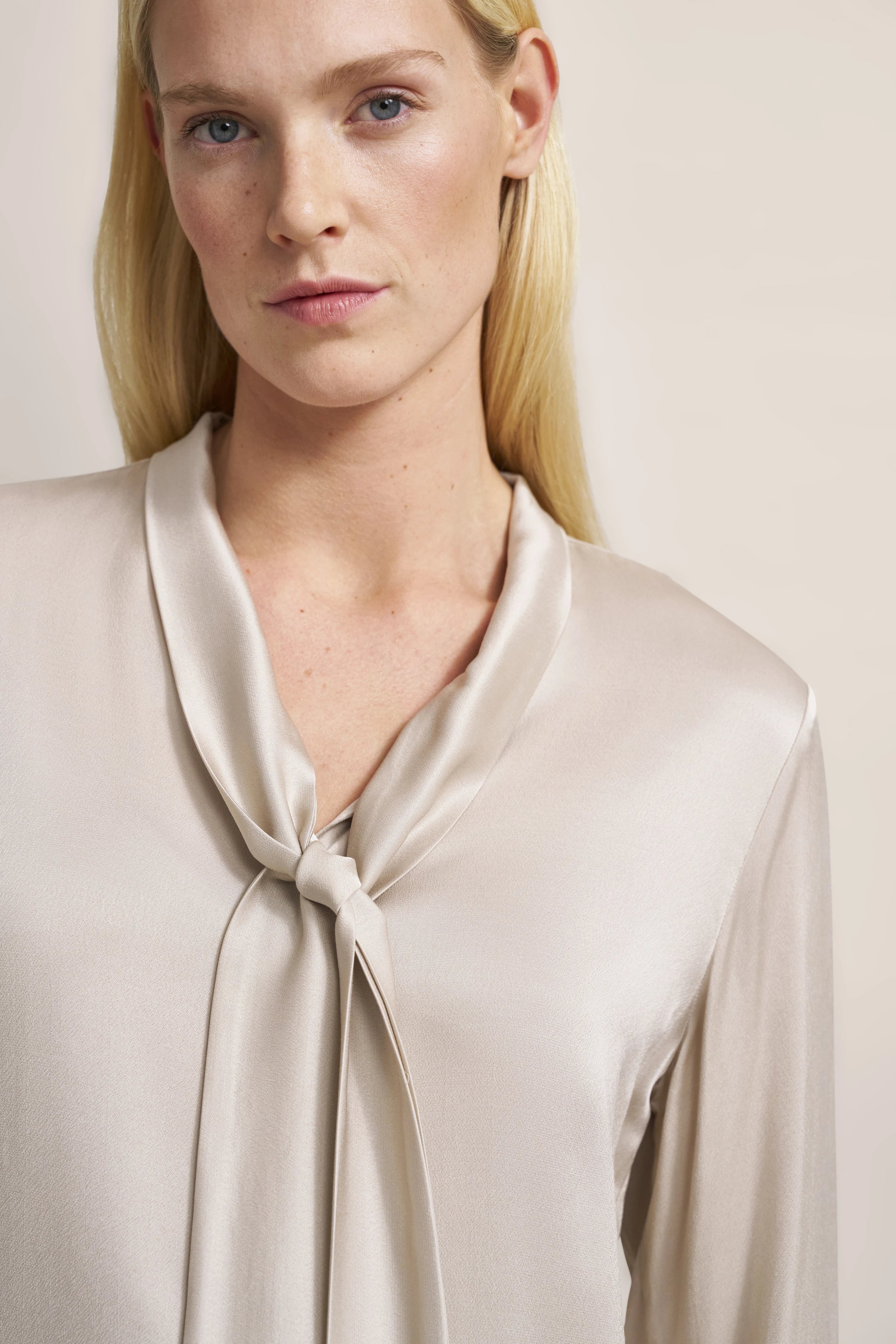 Bluse in Cremefarbe mit elegantem Knotendetail, Modelbild, frontaler Blick.