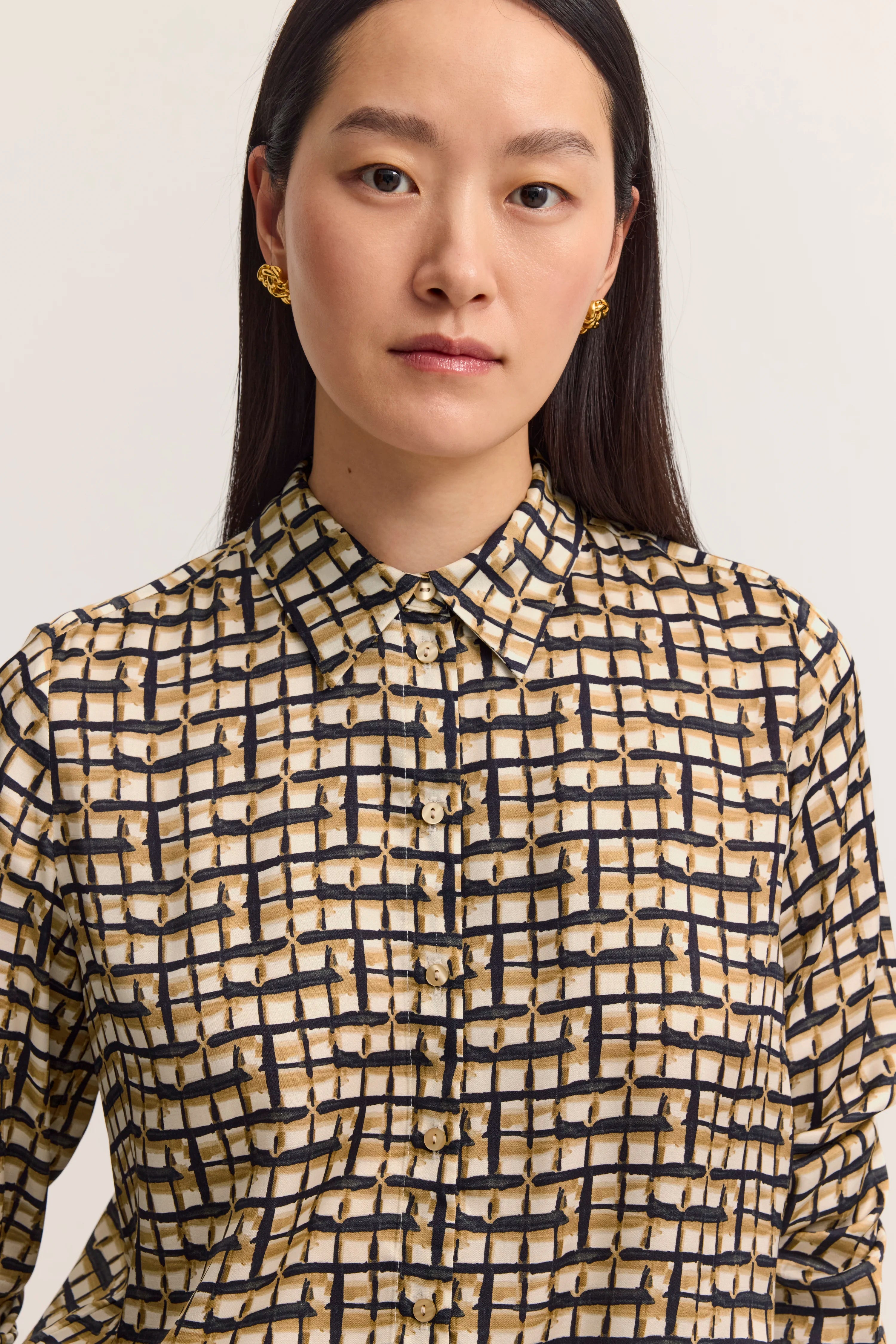 Bluse mit geometrischem Muster in Beige und Schwarz, Büstenbild.