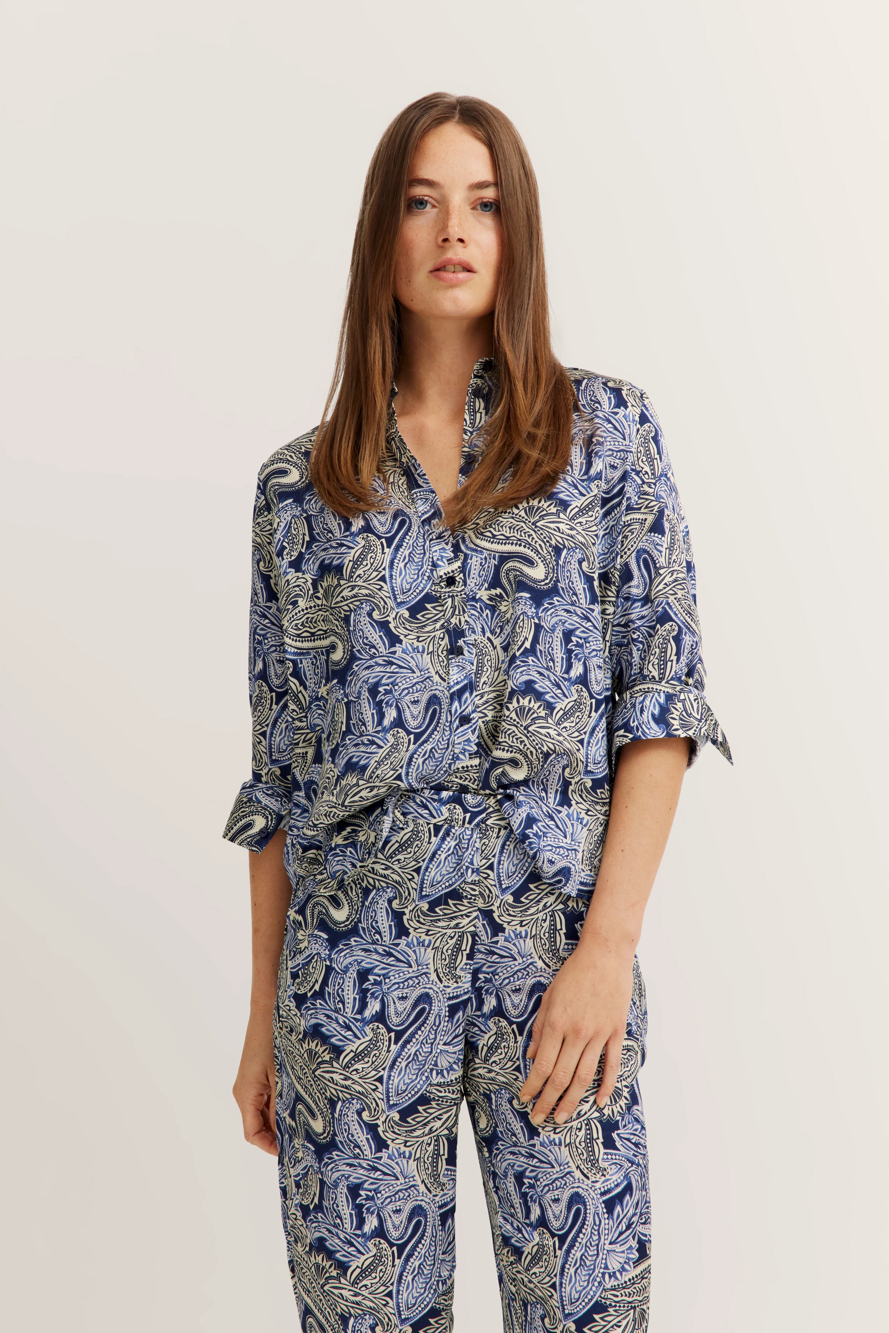 Model trägt bugatti Outfit mit blau-weißem Paisley-Muster, lockerem Hemd und passender Hose.