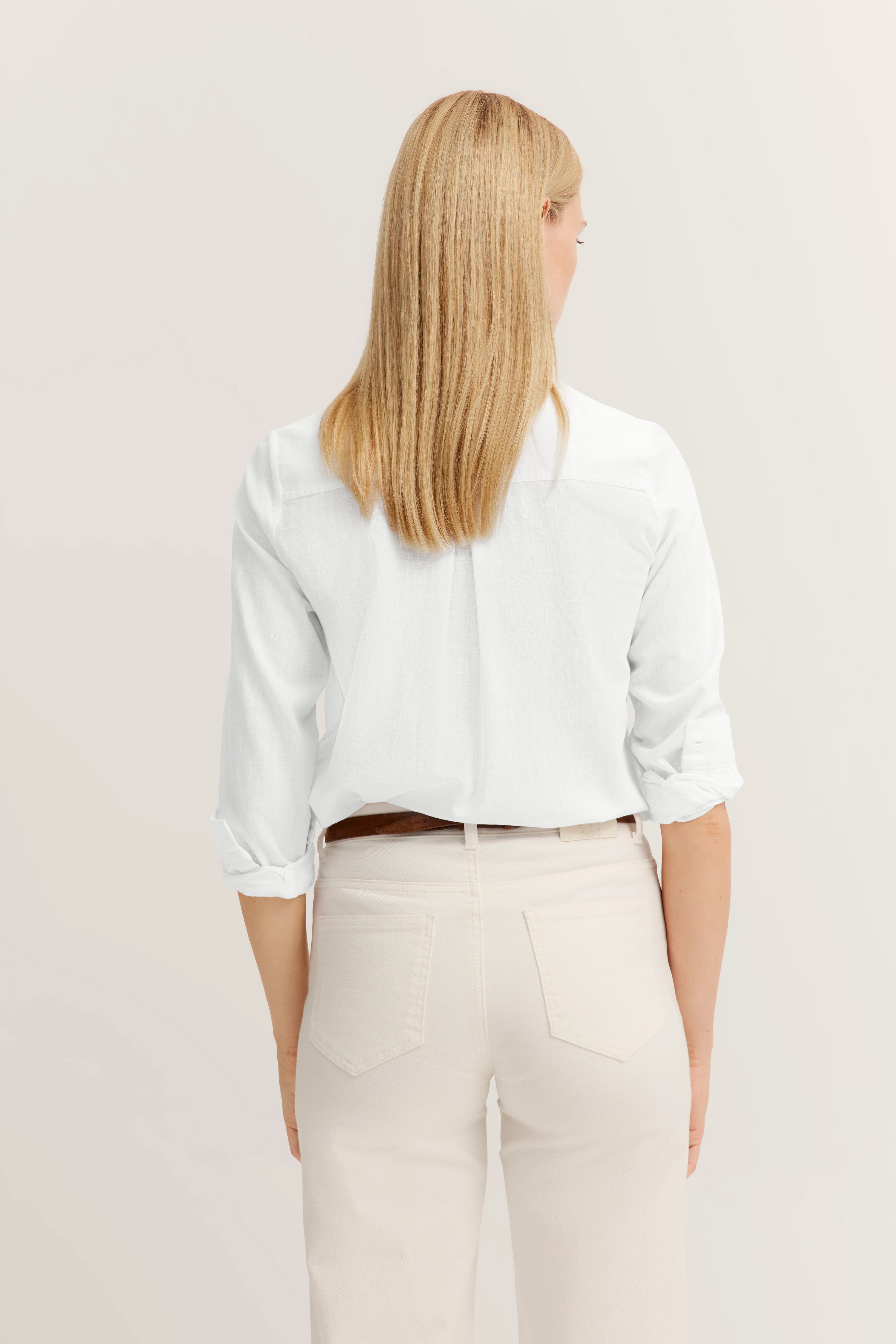 Weiße Bluse und cremefarbene Hose, Rückansicht, legeres Modelbild, entspannter Stil.