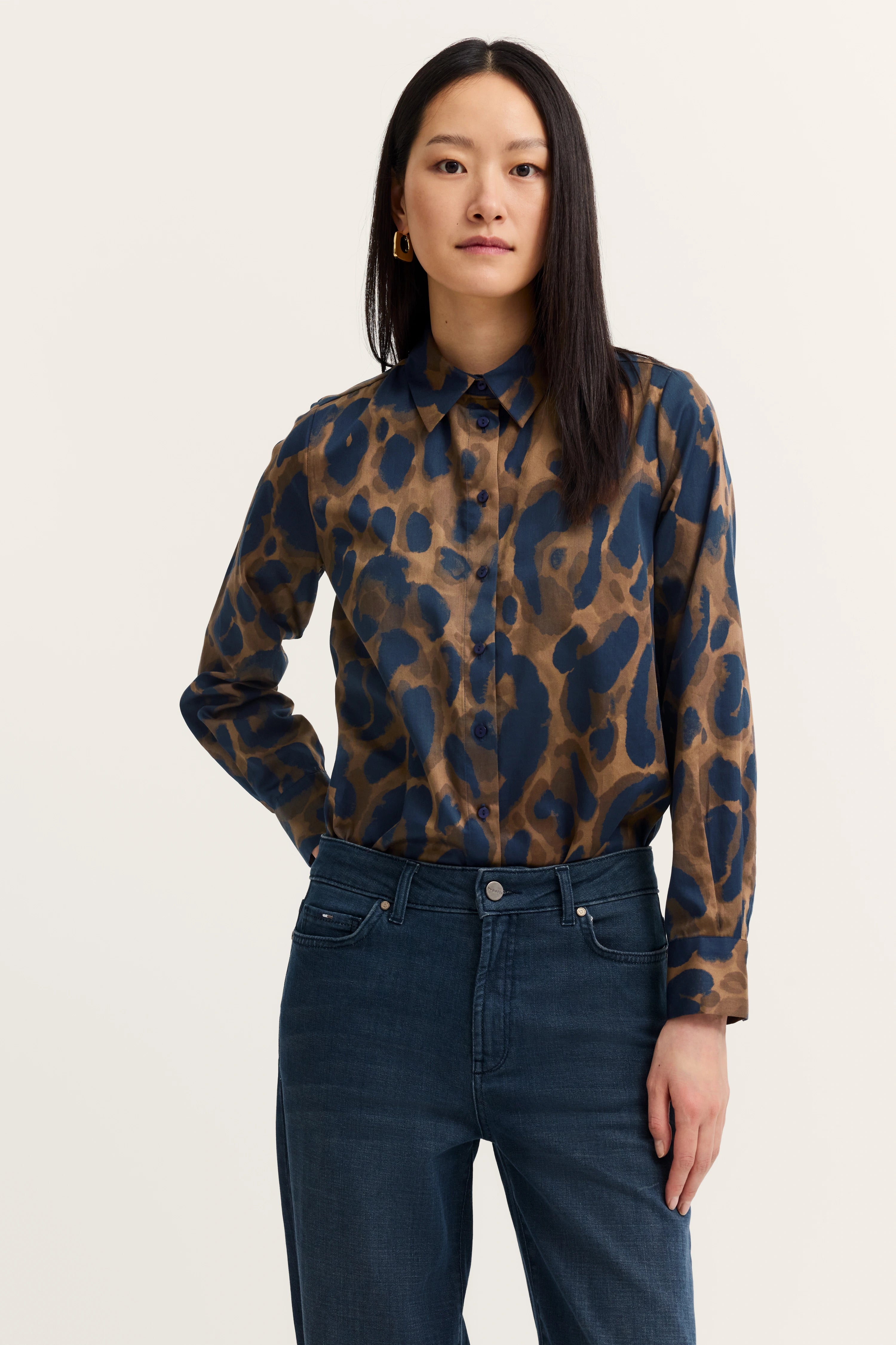 Blau-braune Musterbluse, Jeans, Modell steht frontal, Arme locker, bugatti Stil und Geschmackssicherheit.