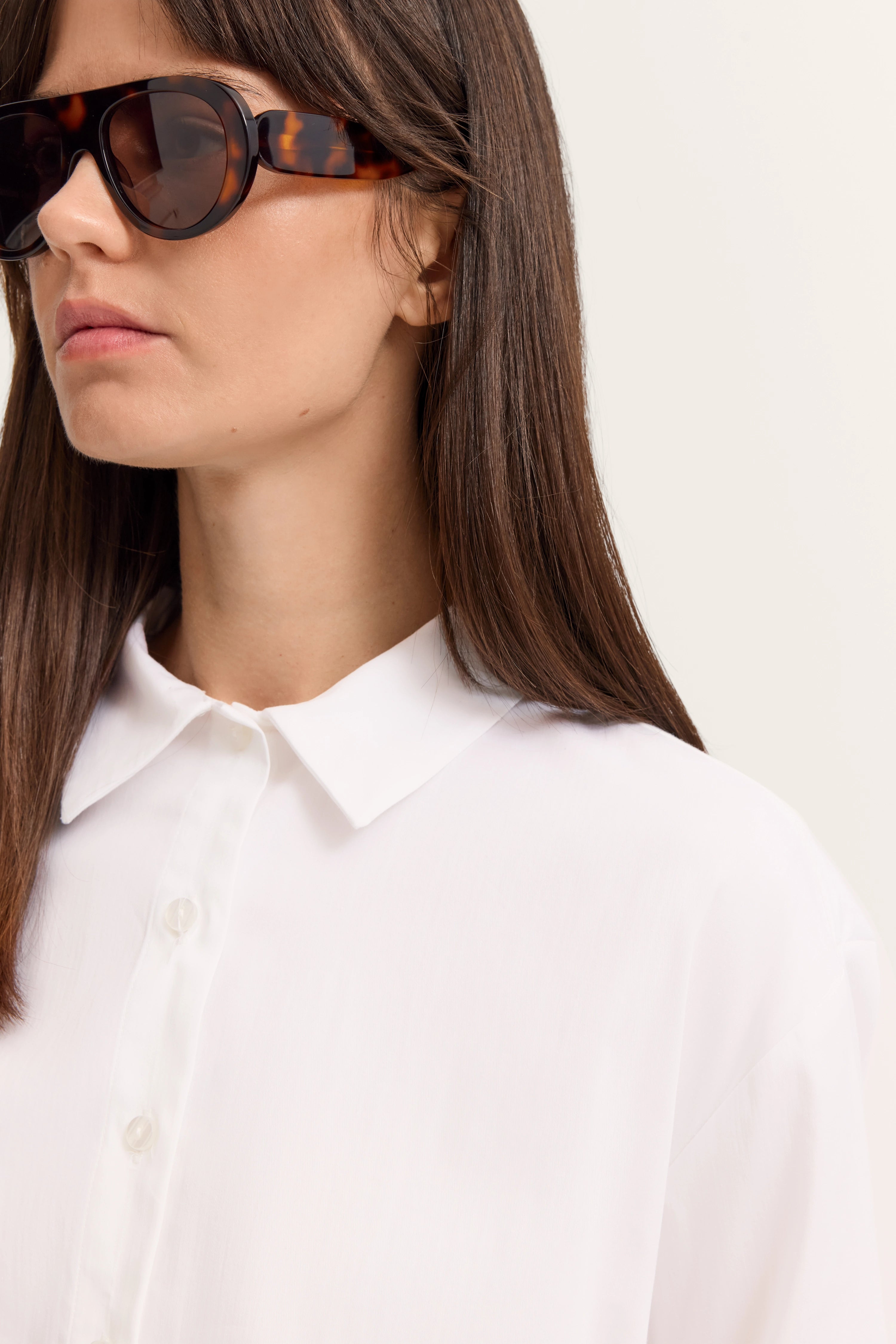 Weiße Bluse mit Kragen, Nahaufnahme, Modell trägt dunkle Sonnenbrille, eleganter Look.