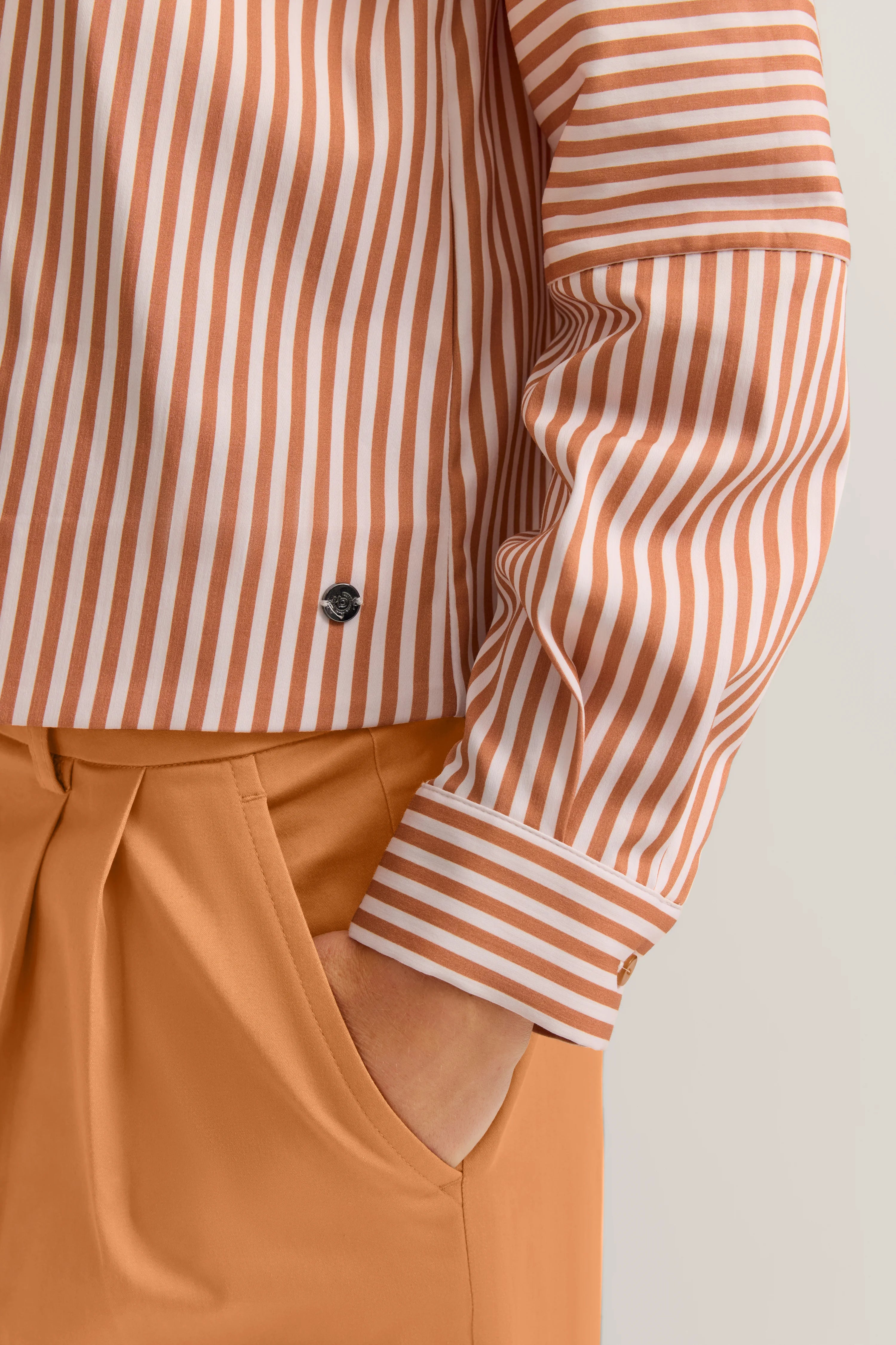 Streifenhemd in Weiß und Orange mit passender Hose, legeres Büstenbild.