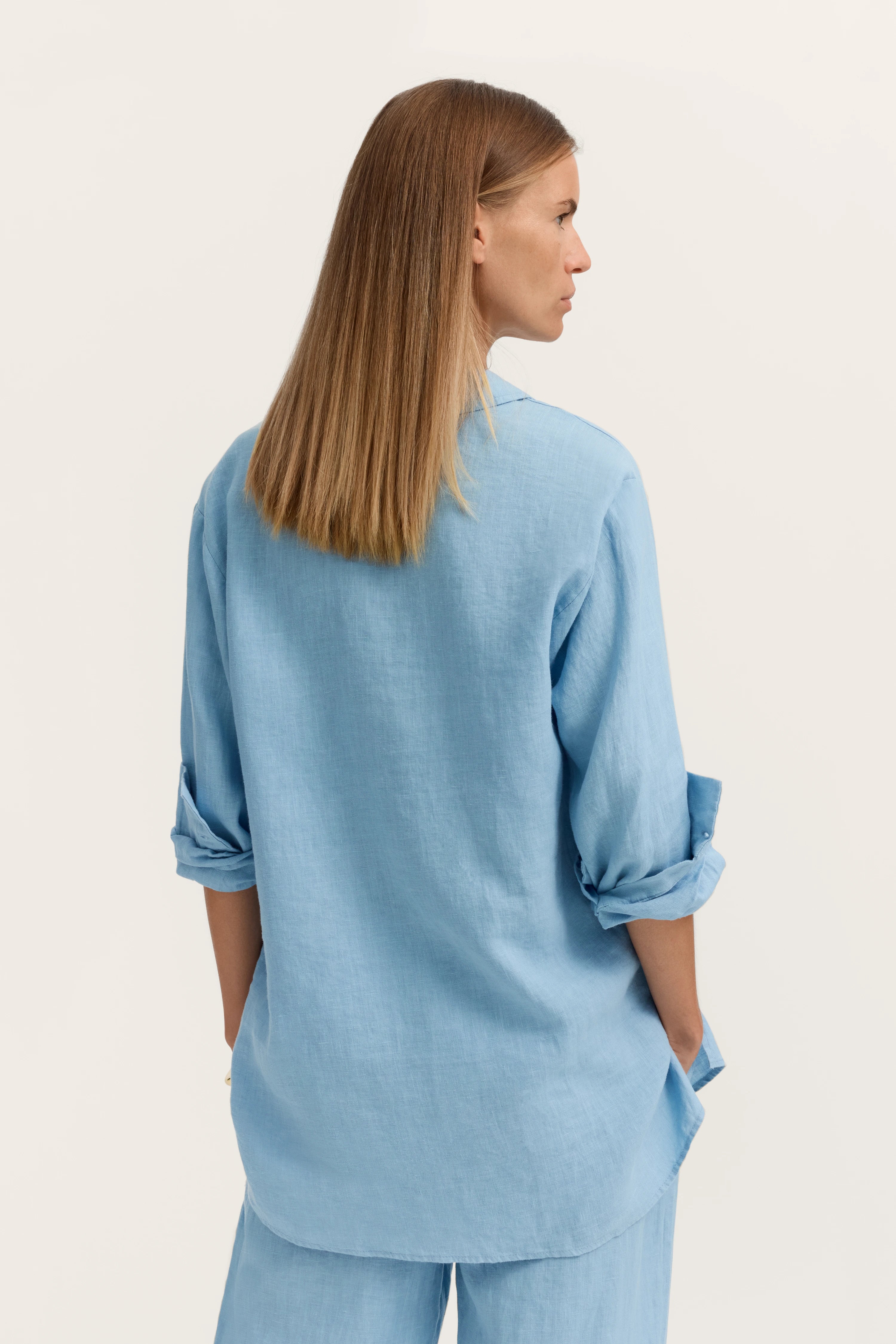 Blaues bugatti Outfit, legeres Modelbild von hinten, Hemd mit hochgekrempelten Ärmeln.