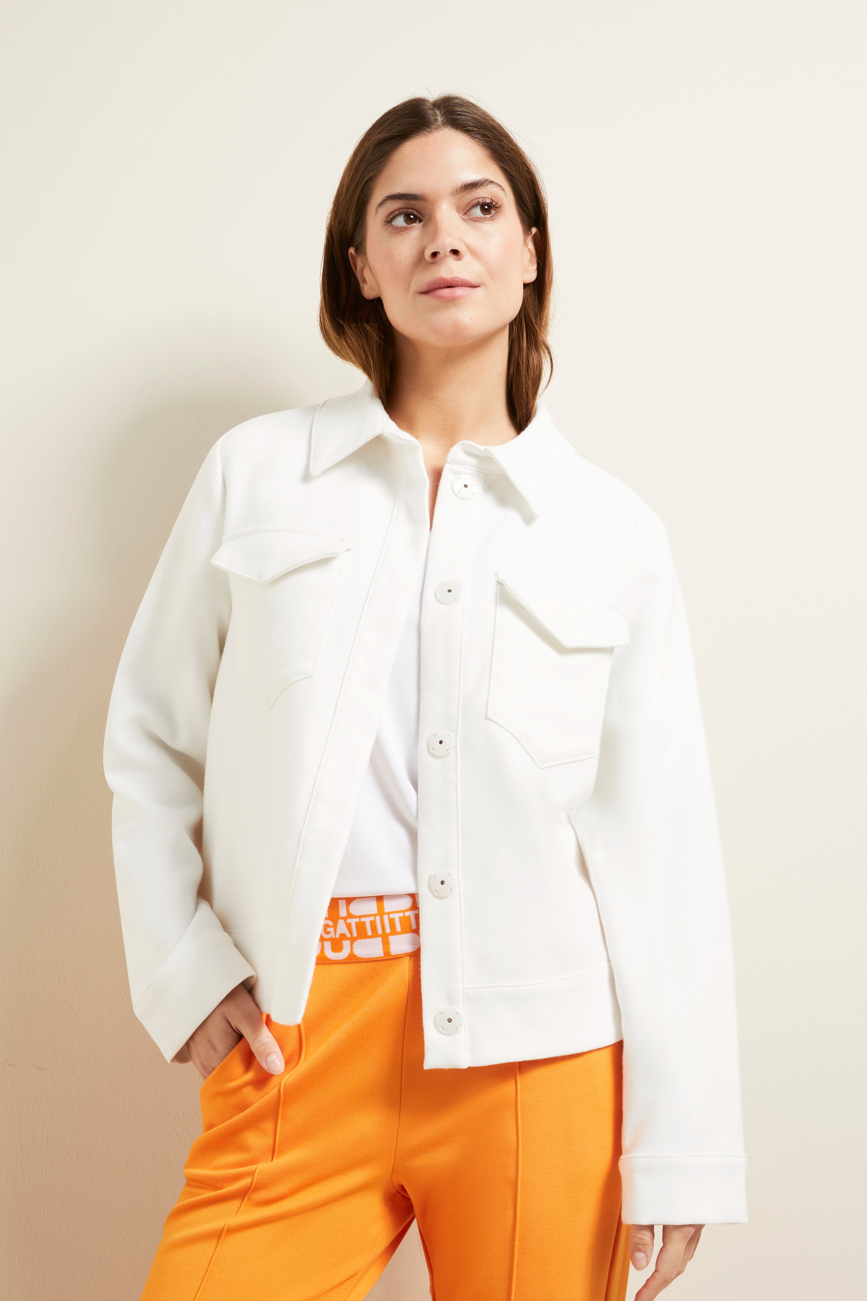 Weiße Jacke und orange Hose von bugatti, Modelbild, entspanntes Posing.