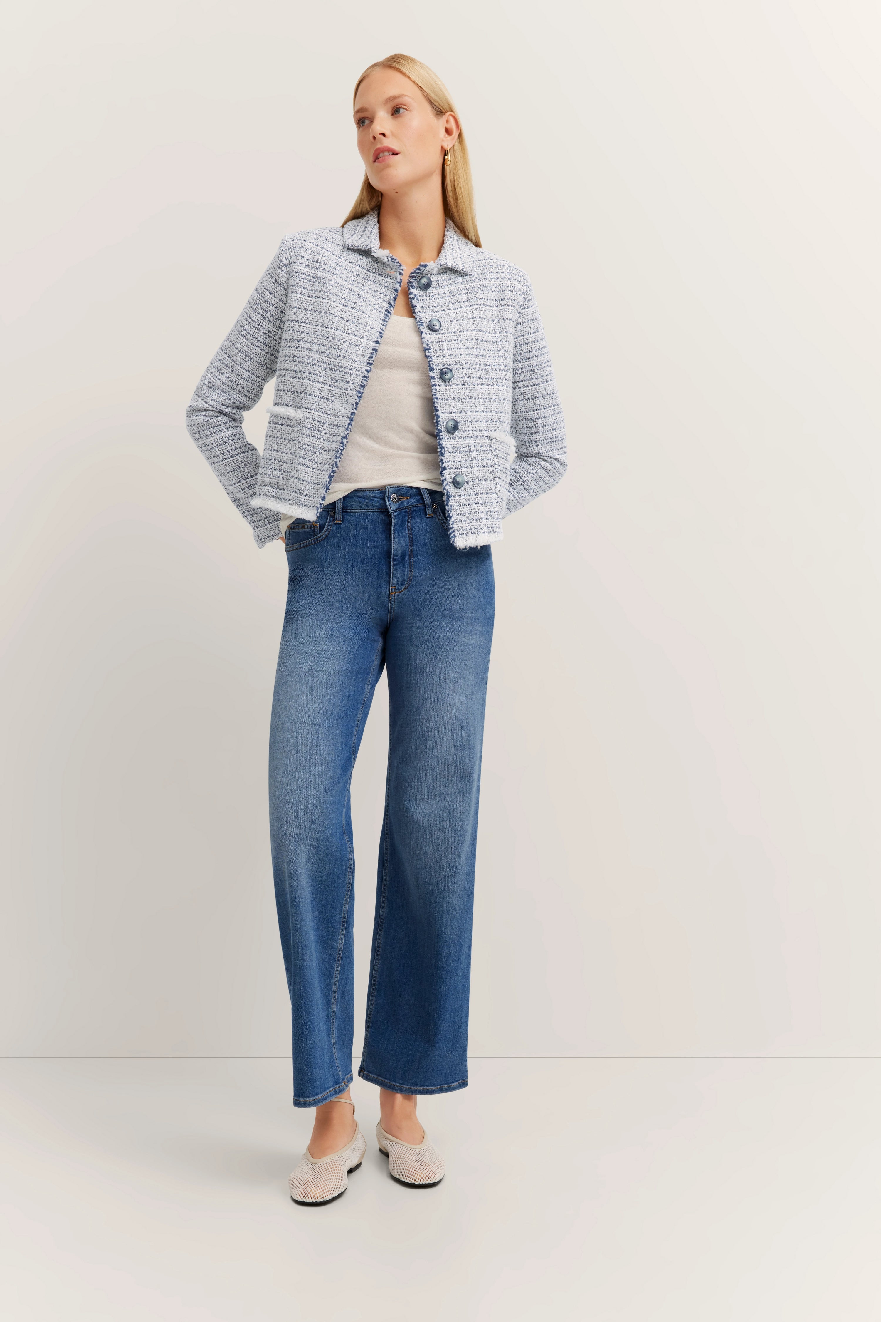 Blauwe tweedblazer en jeans, model van achteren, ontspannen houding.
