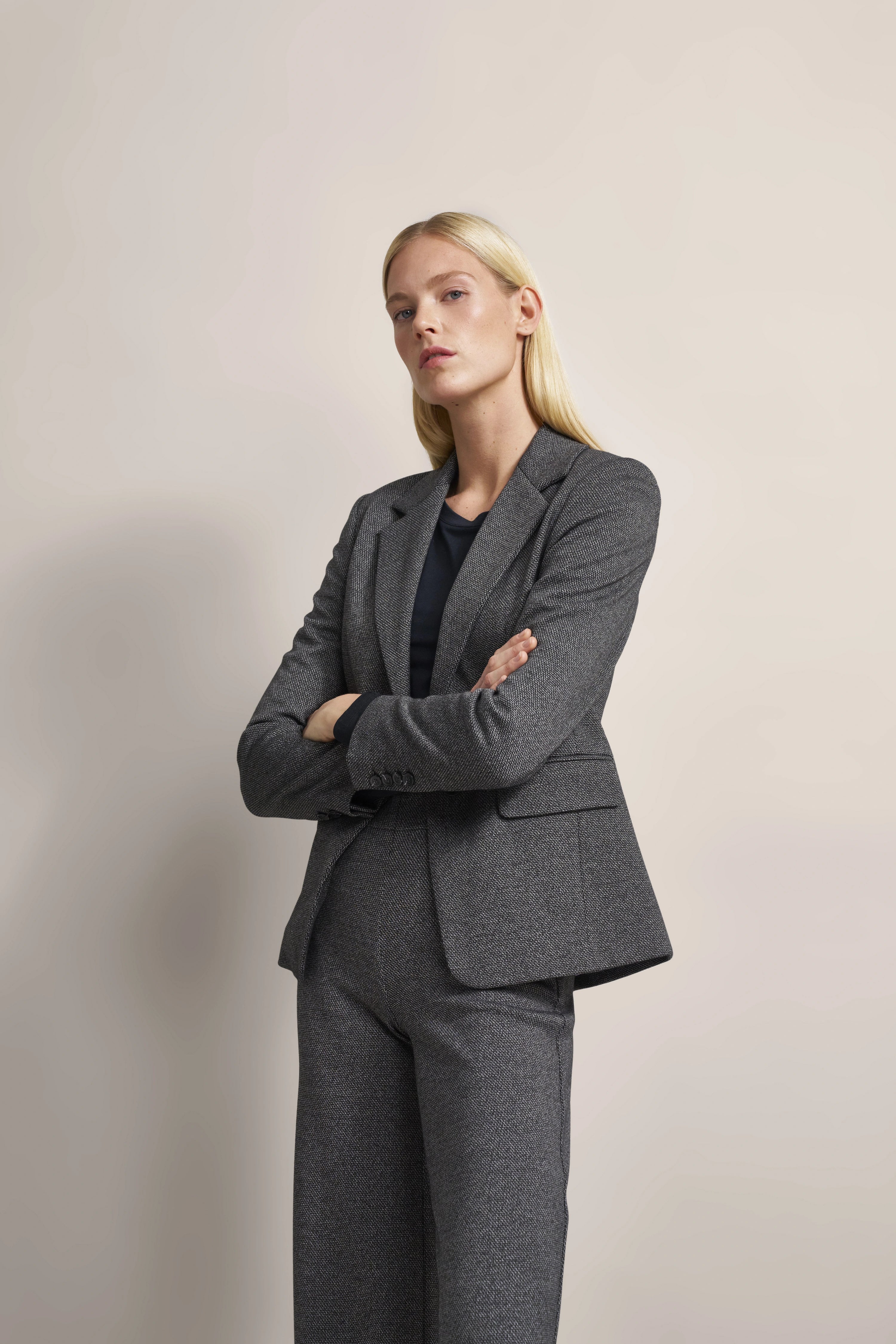 Grijs pak met blazer en broek, model met gekruiste armen, klassiek-elegante kantooroutfit van bugatti.
