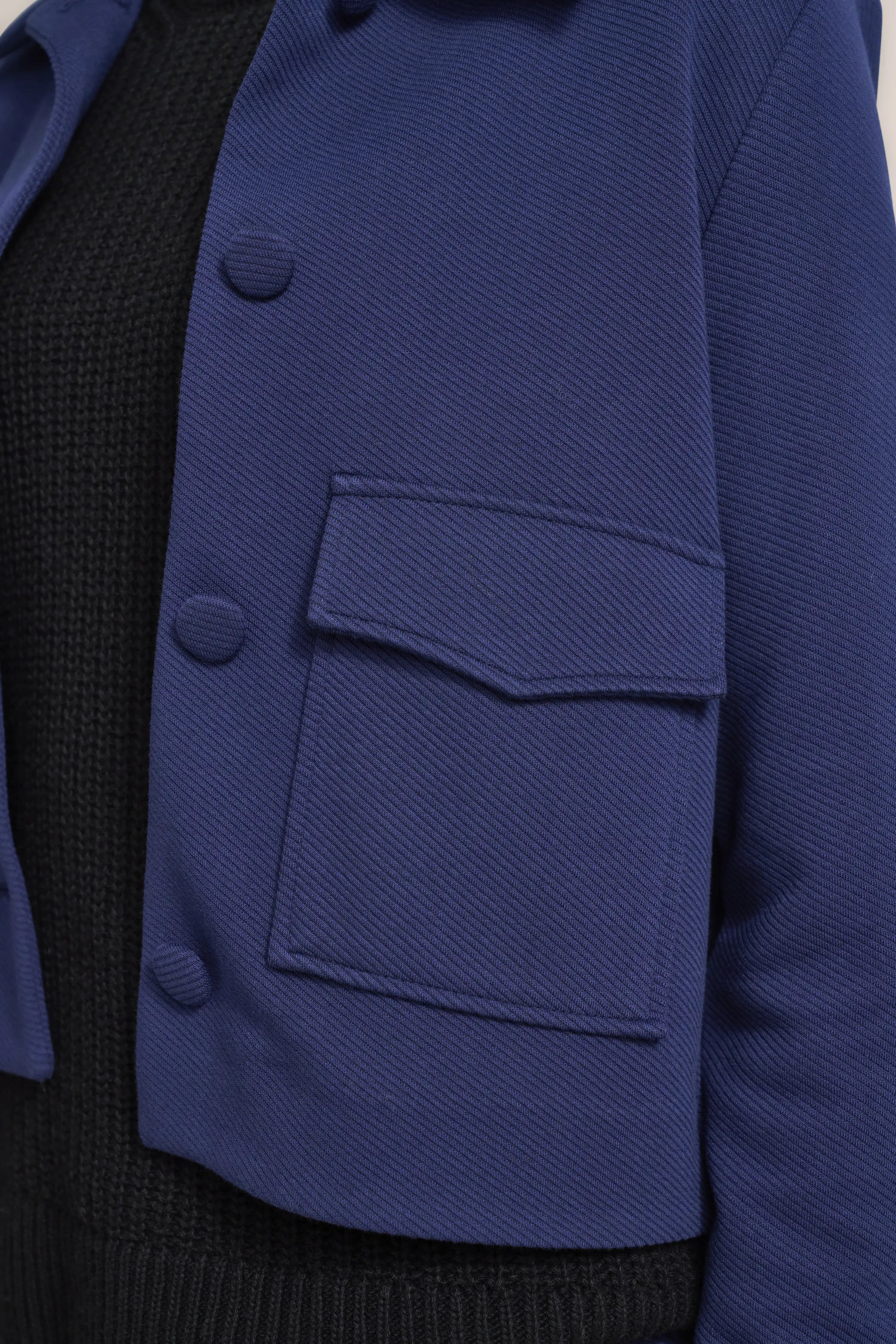 Blaues bugatti Jacket über schwarzem Pullover, Detailaufnahme, eleganter Stil.