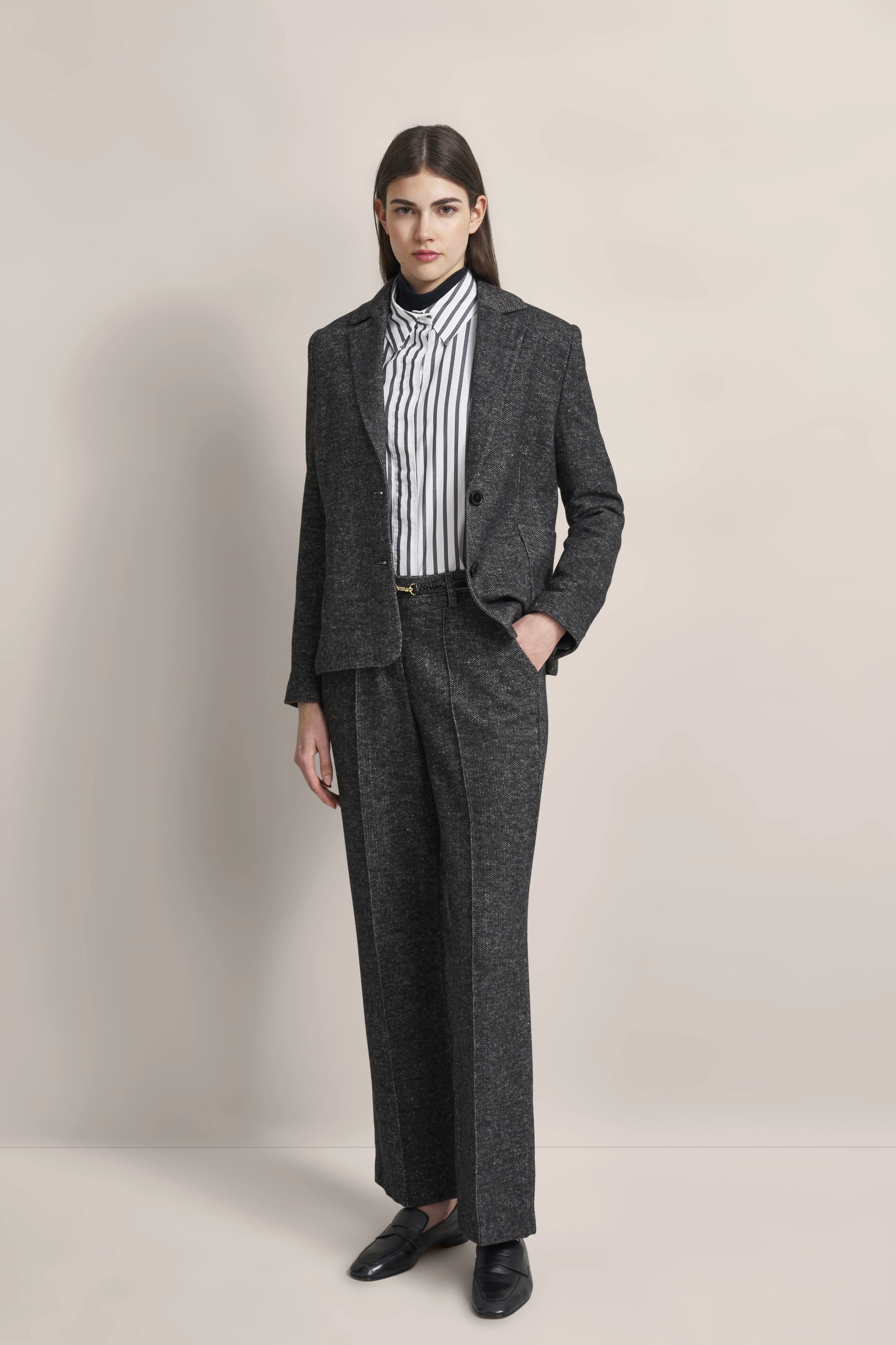 Grauer Anzug mit Streifenhemd, Model posiert stehend, bugatti Stil und Eleganz.
