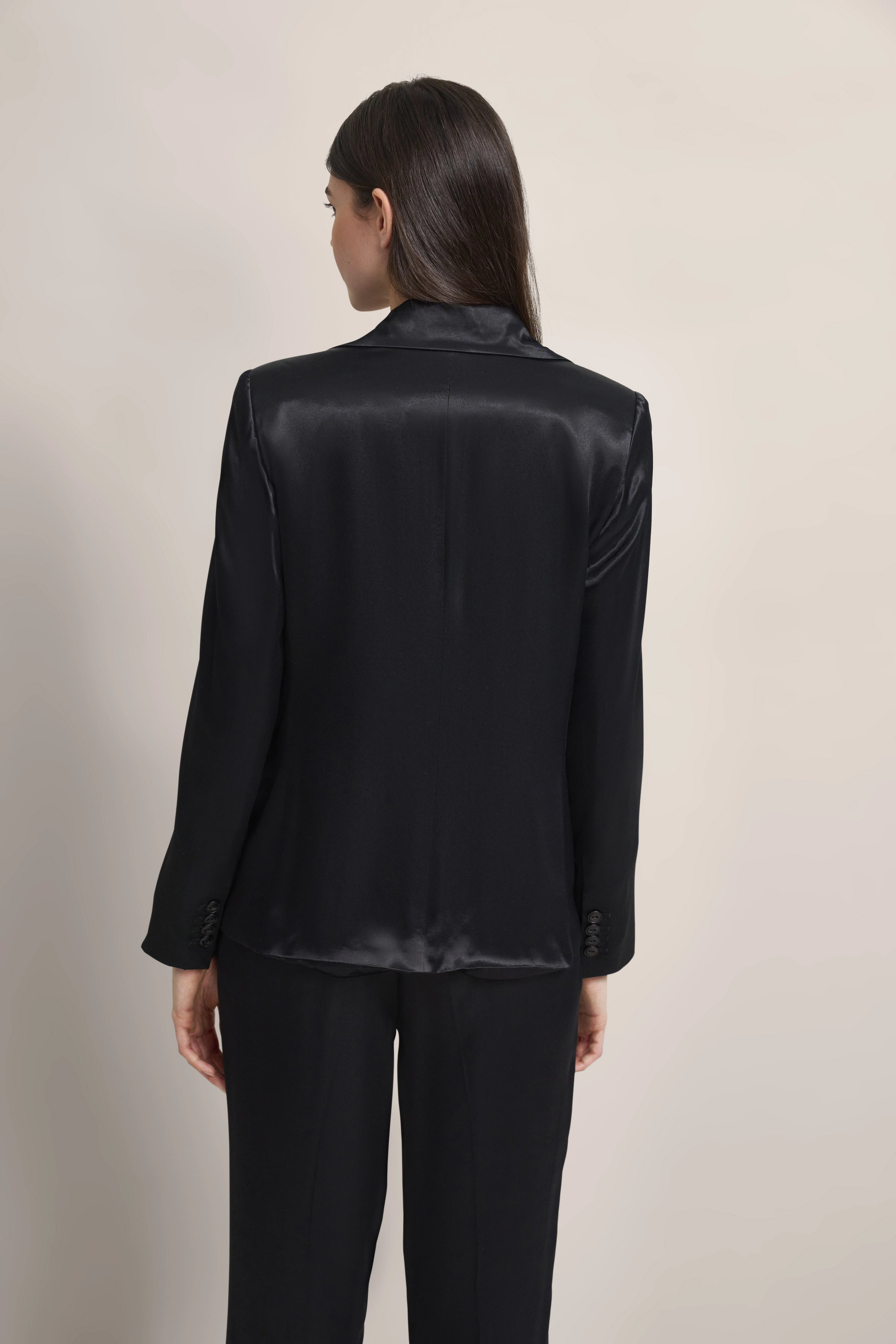 Schwarzes Satin-Outfit, bestehend aus Blazer und Hose. Modelbild, Rückansicht.