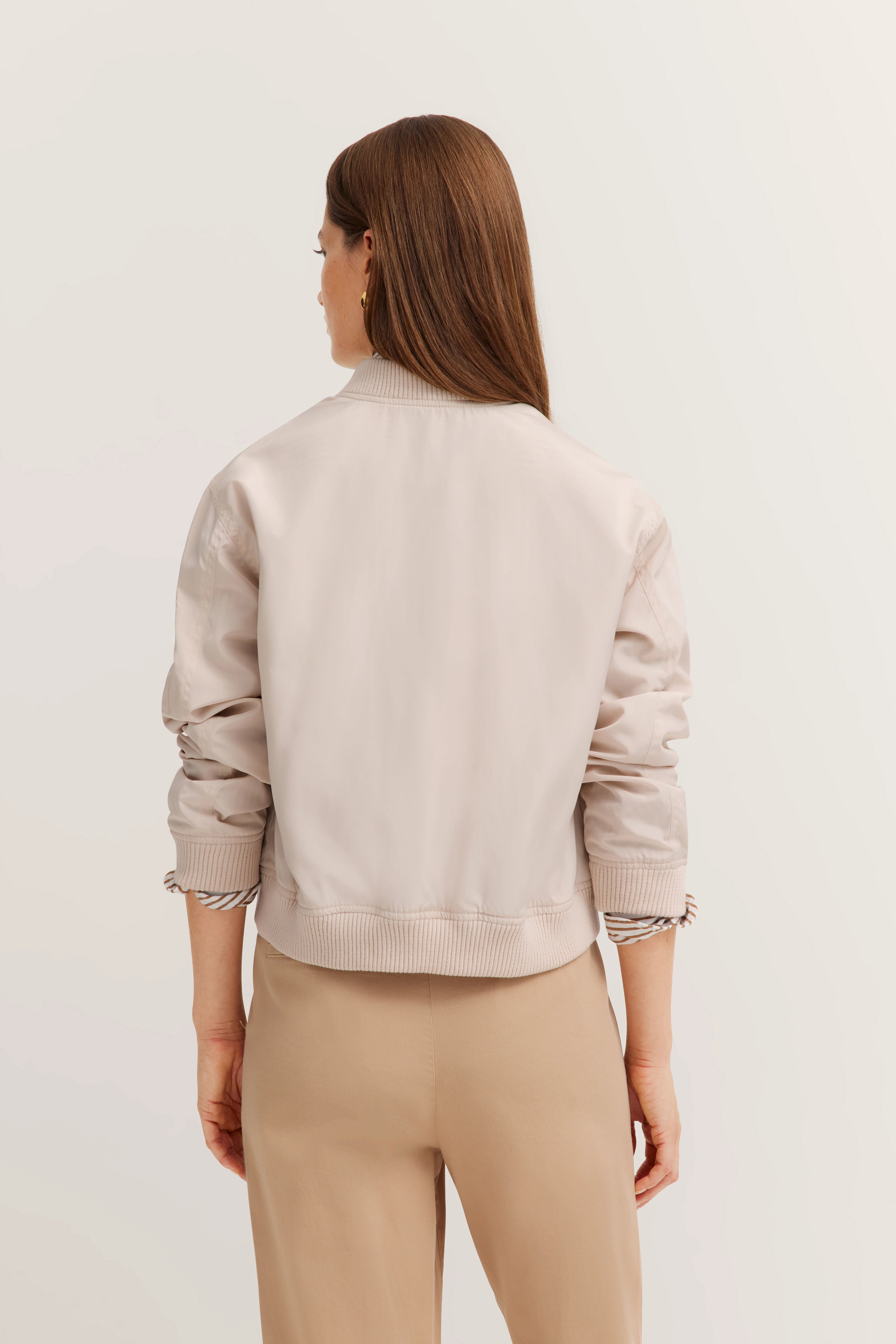 Damen in beiger bugatti-Jacke, Rückansicht, locker über beigen Hosen, legeres Modelbild.