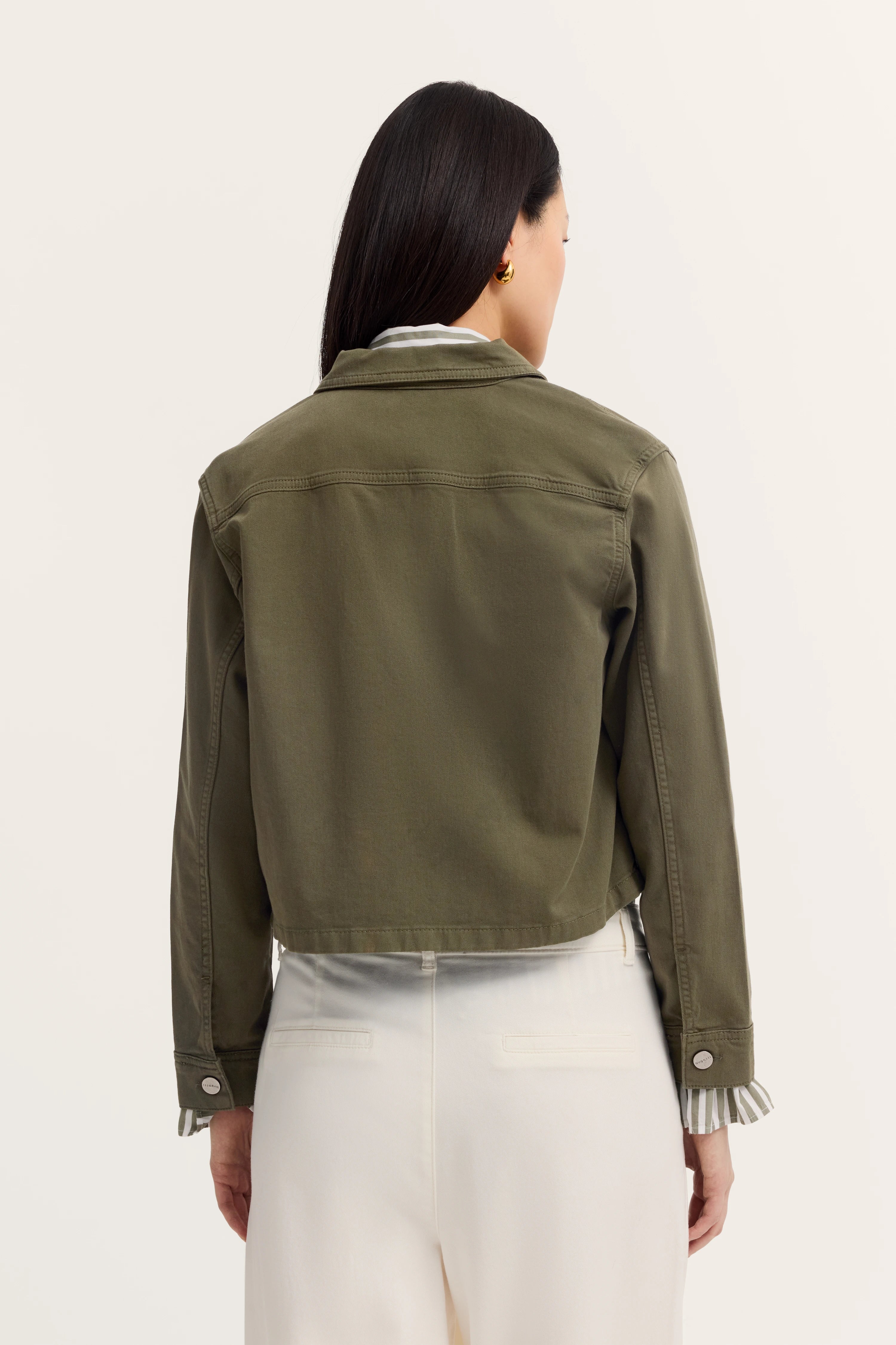 Groene bugatti-jas op model, achterkant, gecombineerd met witte broek.