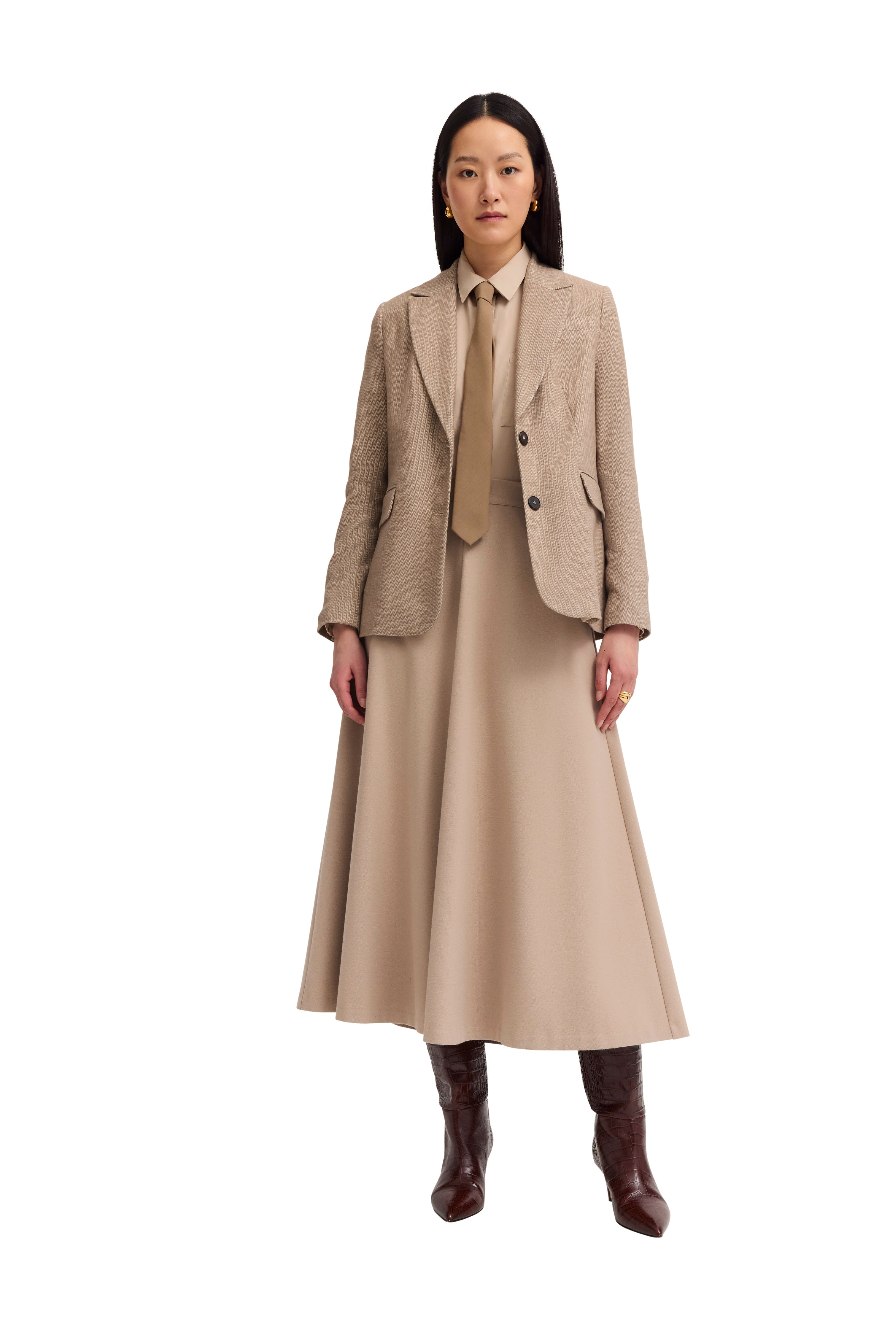 Beige bugatti outfit met blazer, rok en stropdas, model poseert elegant staand.