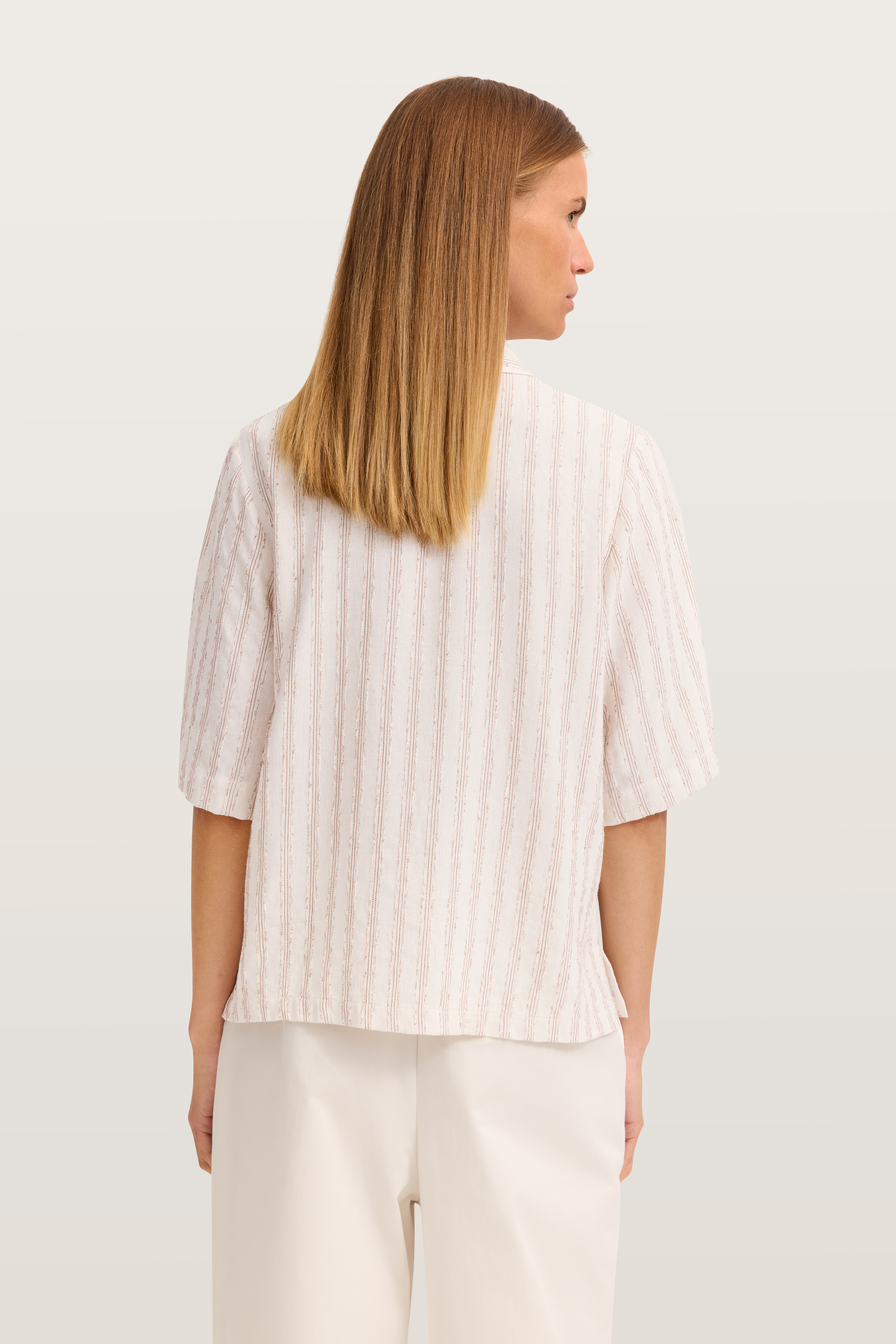 Weißes, gestreiftes Top und weiße Hose, Rückansicht, Model steht entspannt.