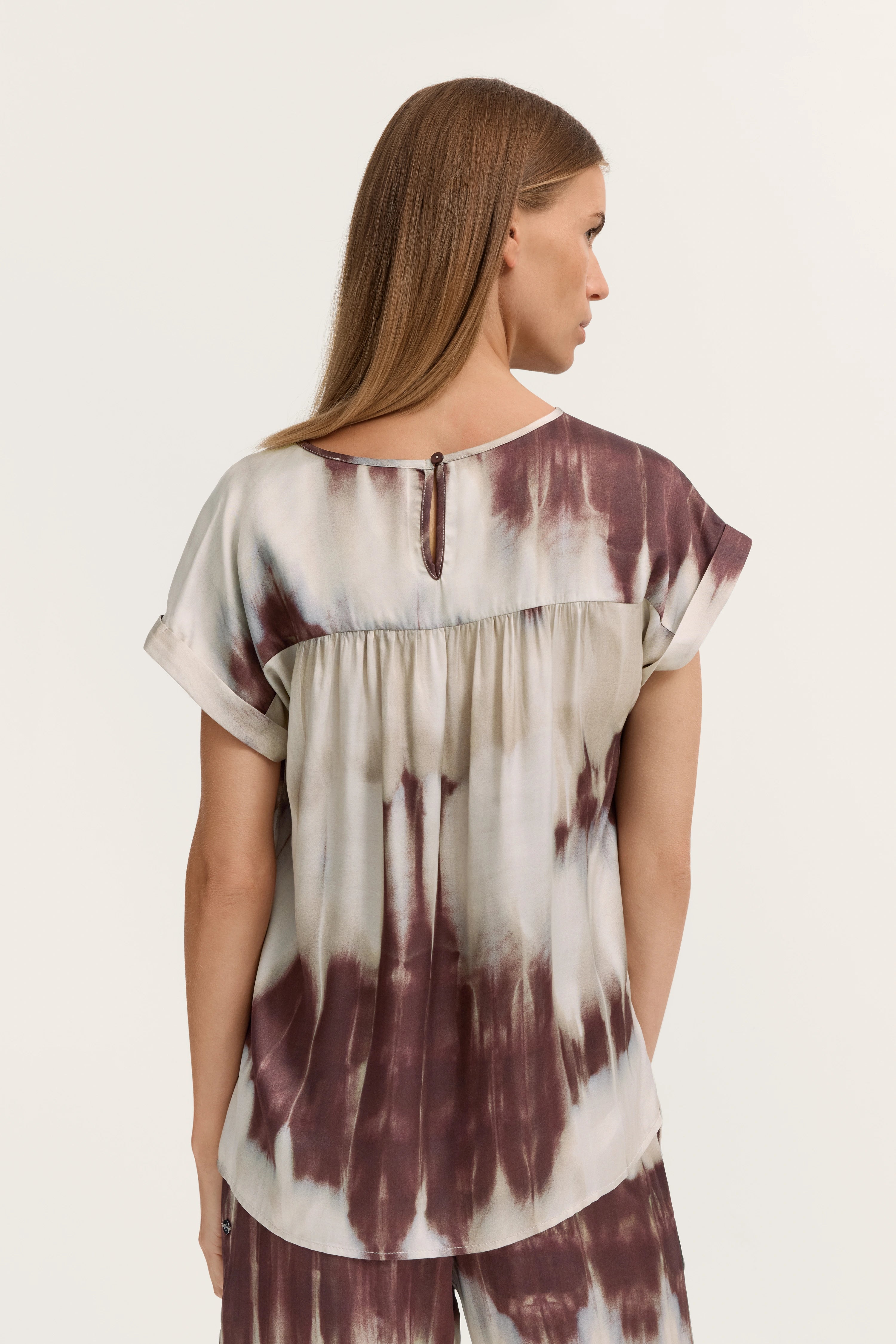 Damenbluse mit Batikmuster in Braun-Weiß, Rückansicht. Modelbild, seitliche Pose.