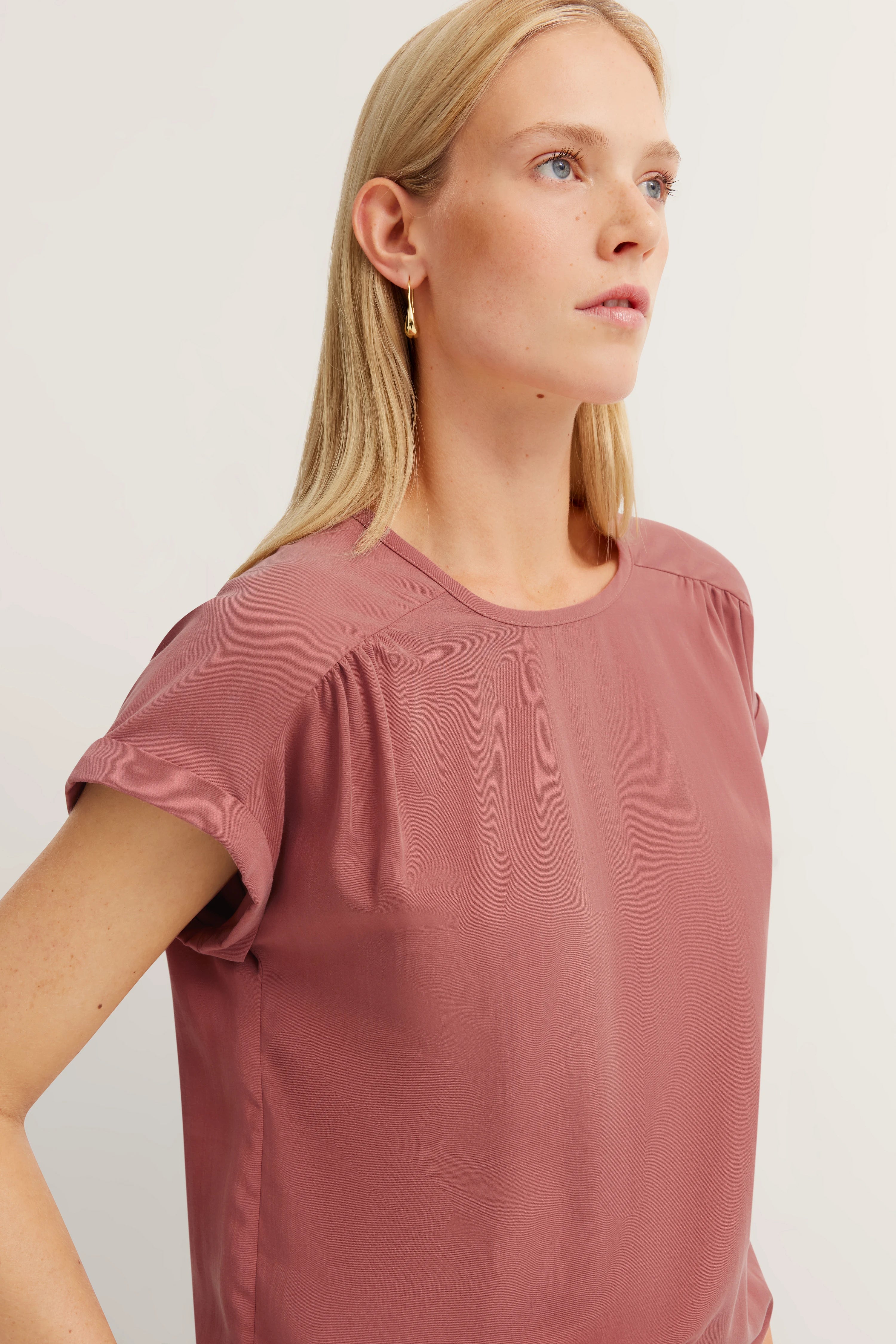 Borstbeeld van een vrouw in oudroze T-shirt van bugatti, elegant design, ontspannen uitstraling.