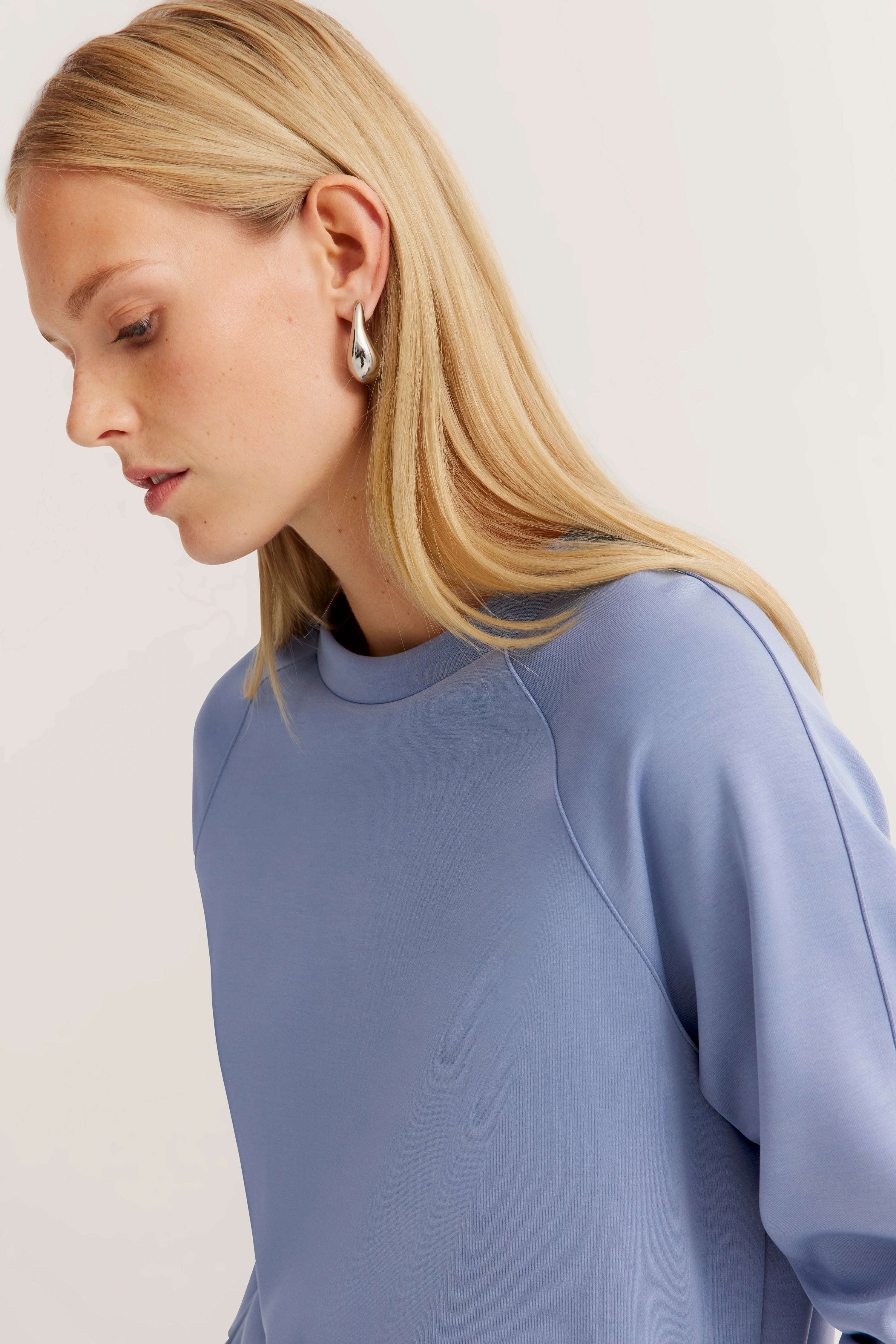 Borstbeeld van vrouw in lichtblauwe bugatti top, zijprofiel, elegant ontwerp.