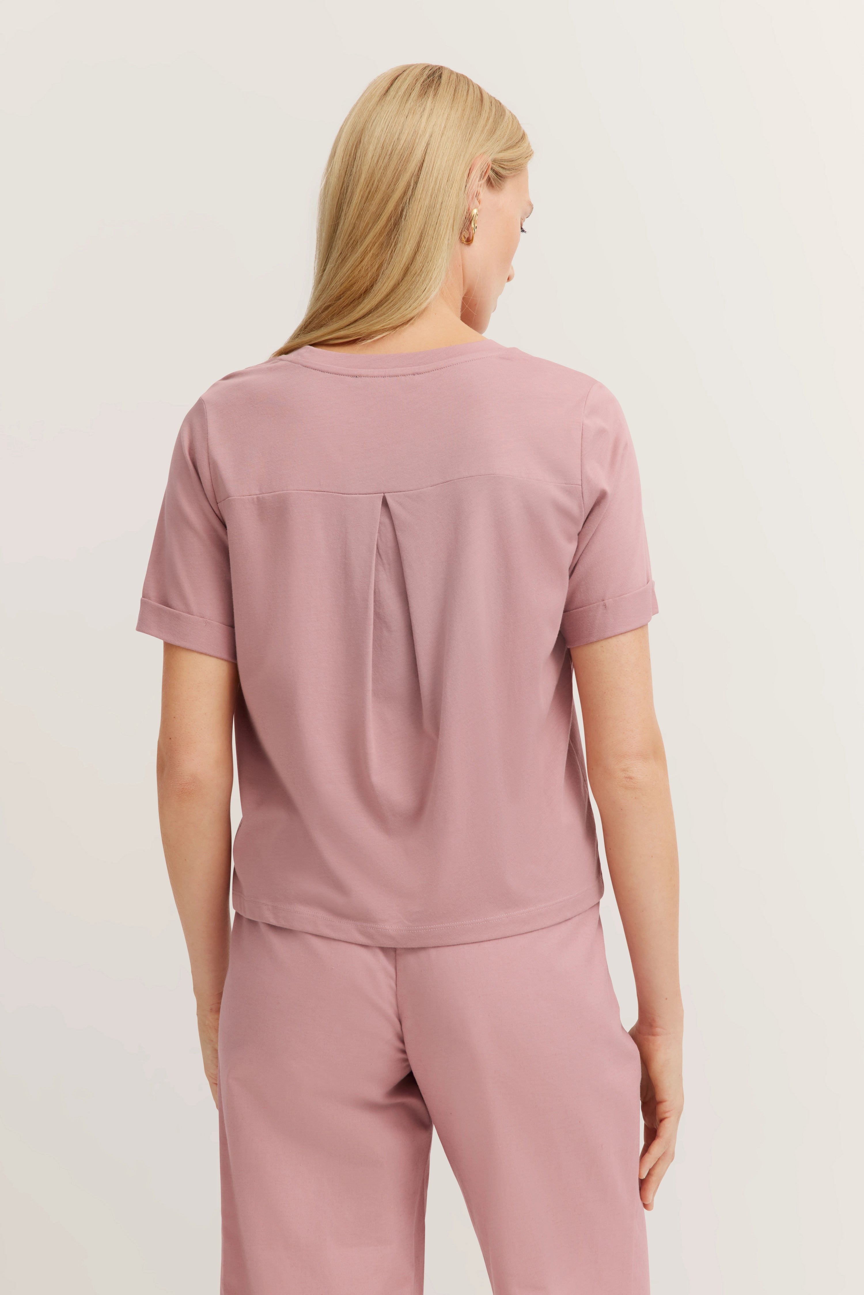 Achteraanzicht van een model in roze bugatti outfit met korte mouwen top en bijpassende broek.