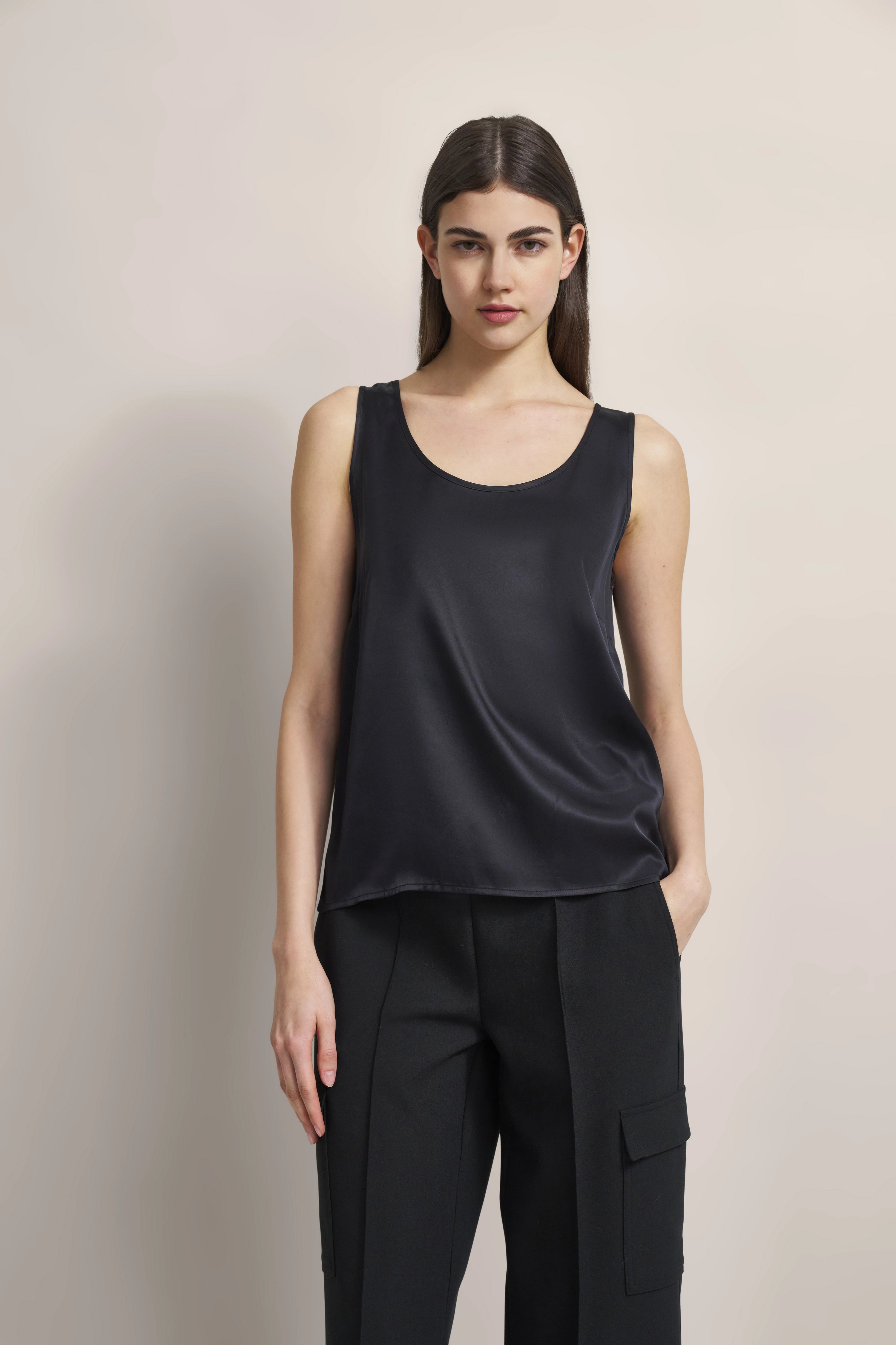 Schwarzes ärmelloses Top und schwarze Hose, Modelbild, entspannte Pose, bugatti Stil.