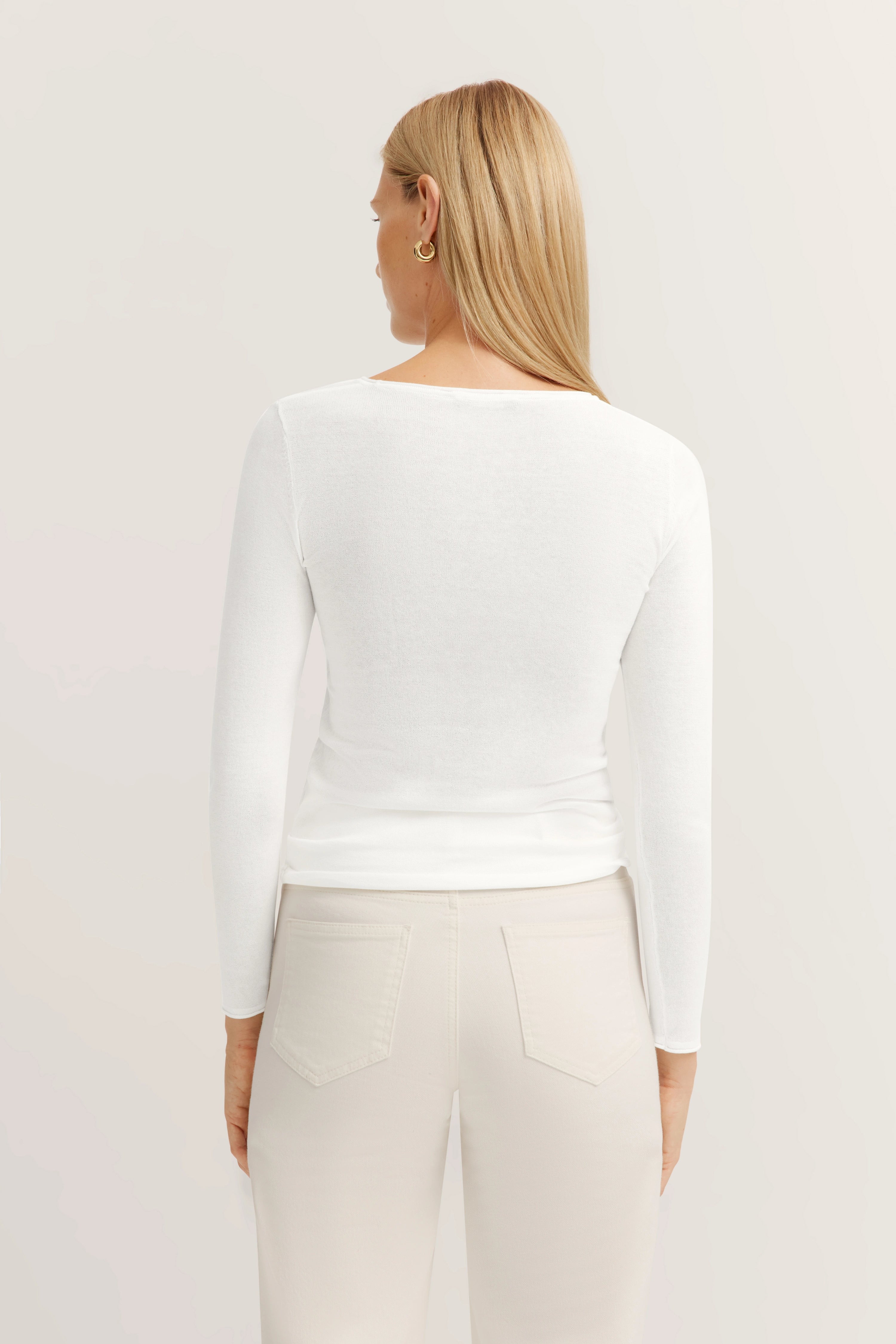 Weiße bugatti Bluse und beige Hose, Rückenansicht, Modelbild, lässige Pose.