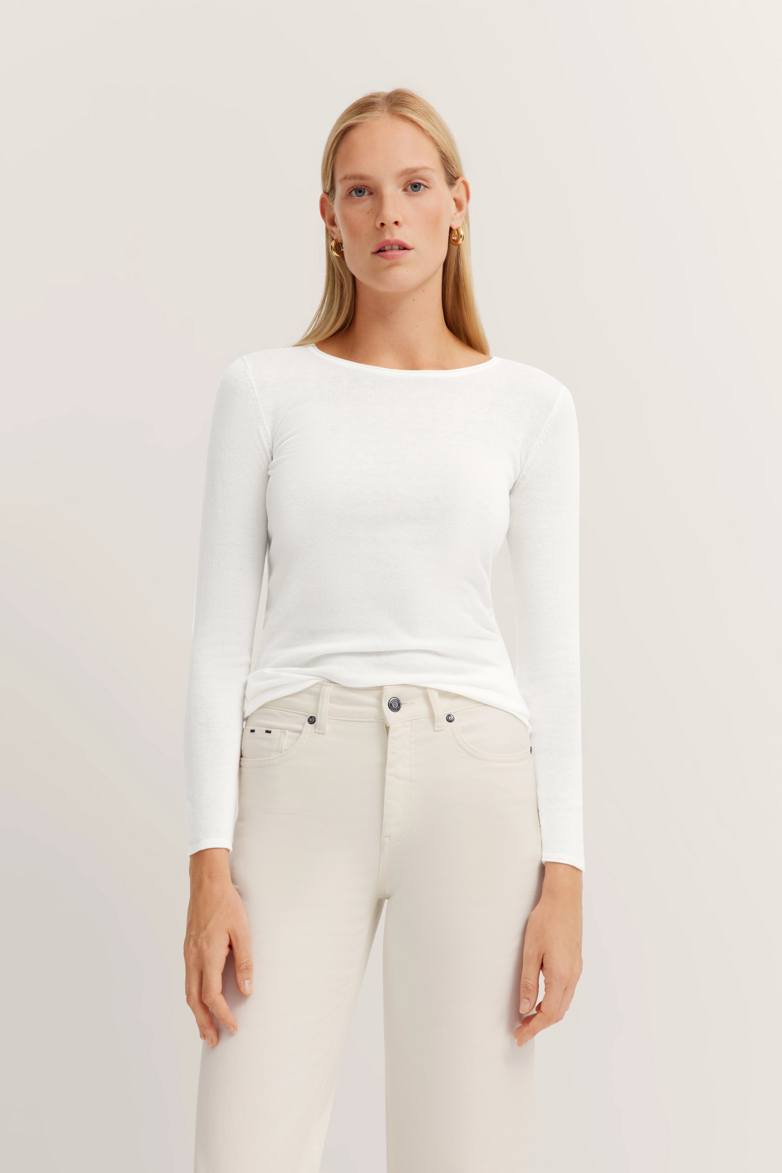 Weißes Langarmshirt und cremefarbene Hose, Model frontal stehend, minimalistische Eleganz.