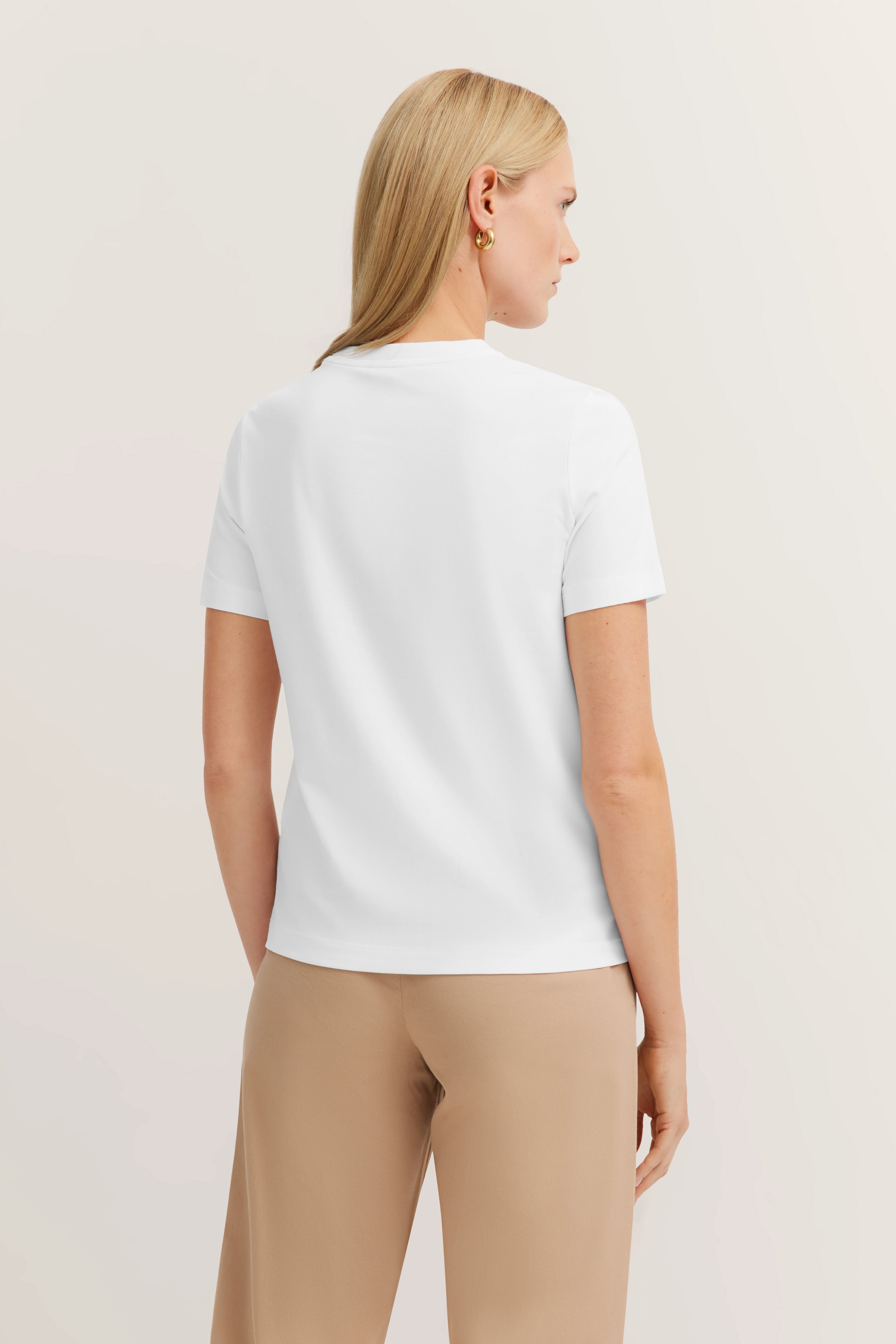 Weiße bugatti Bluse, beige Hose, Model von hinten.