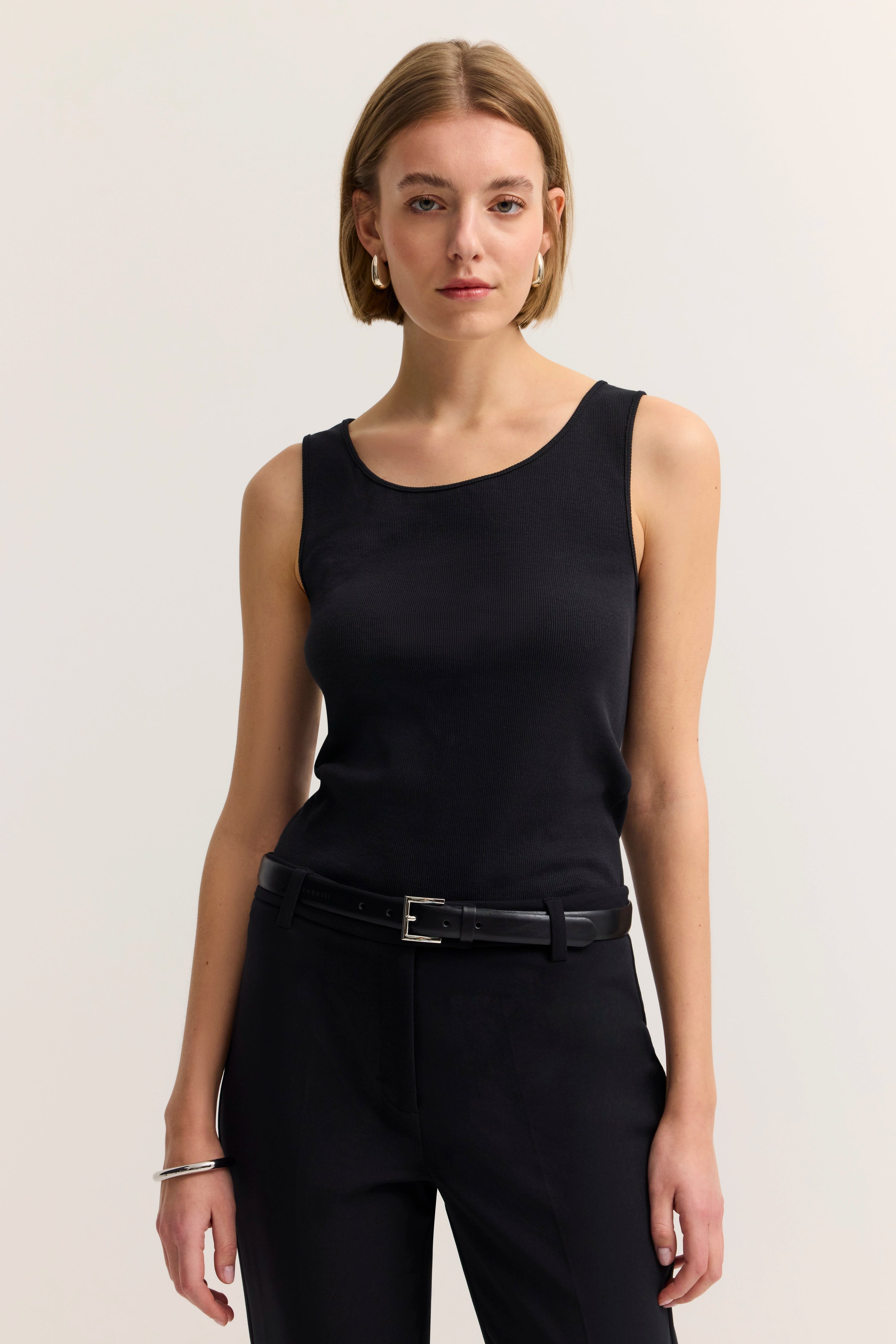 Schwarzes ärmelloses Top und Hose, Modelbild mit entspanntem Stand.